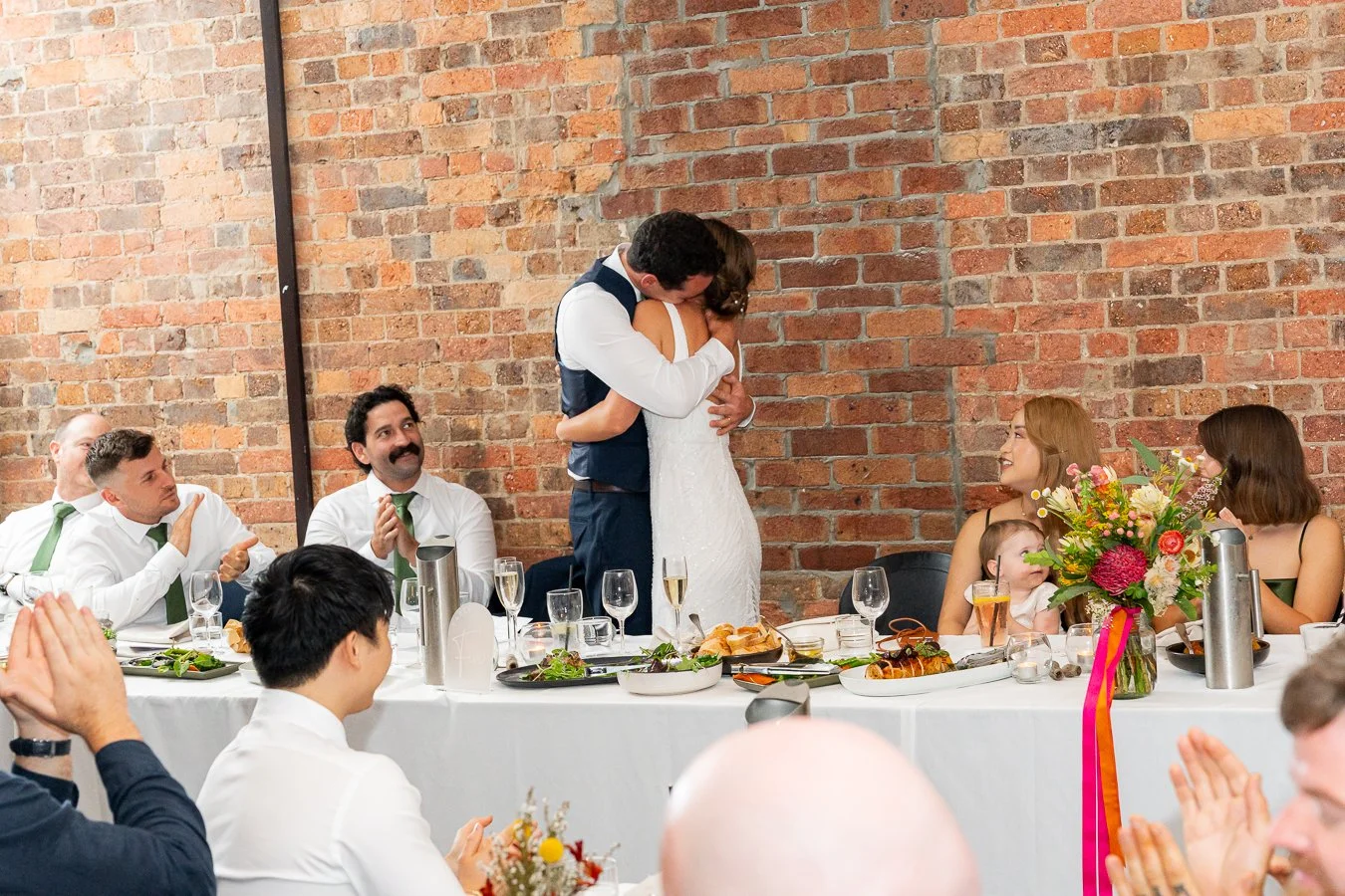 bride and groom hugging each other and all bridal party claps