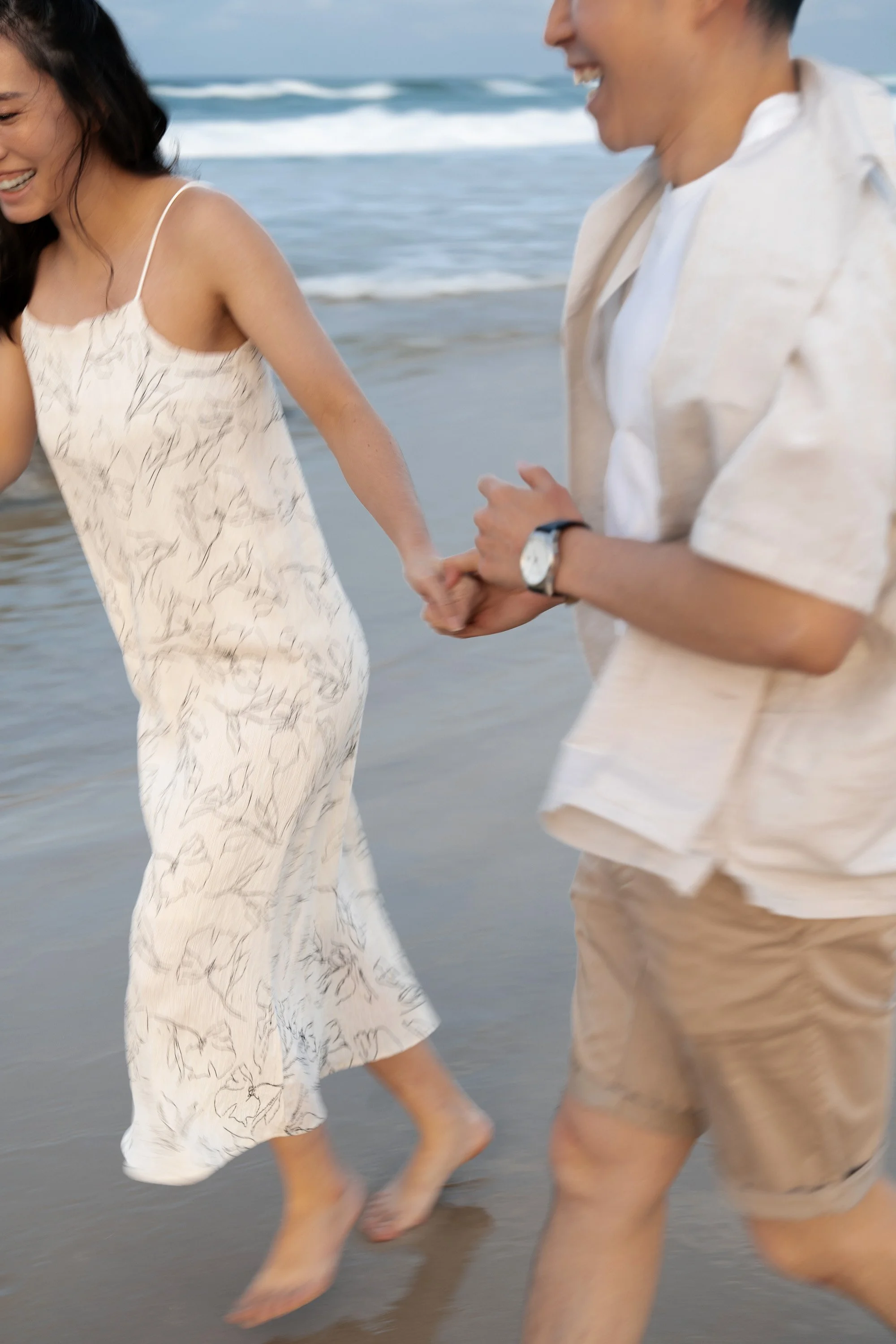 Paul and Krystel hold hands running with big laugh in their engagement photo shoot session