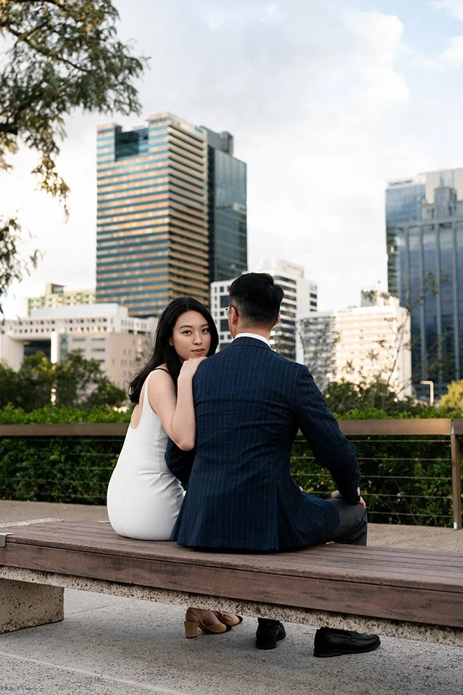 Kath hands on Dave's shoulder while they both seating on the the wooden bench