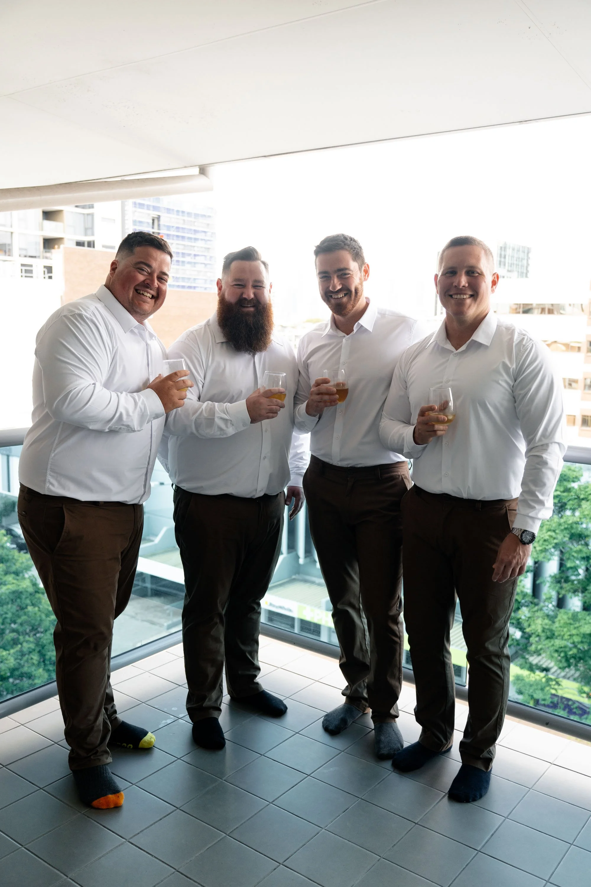 Groom Thomas and his groomsmen standing on the balcony, enjoying a relaxed moment together before the wedding ceremon