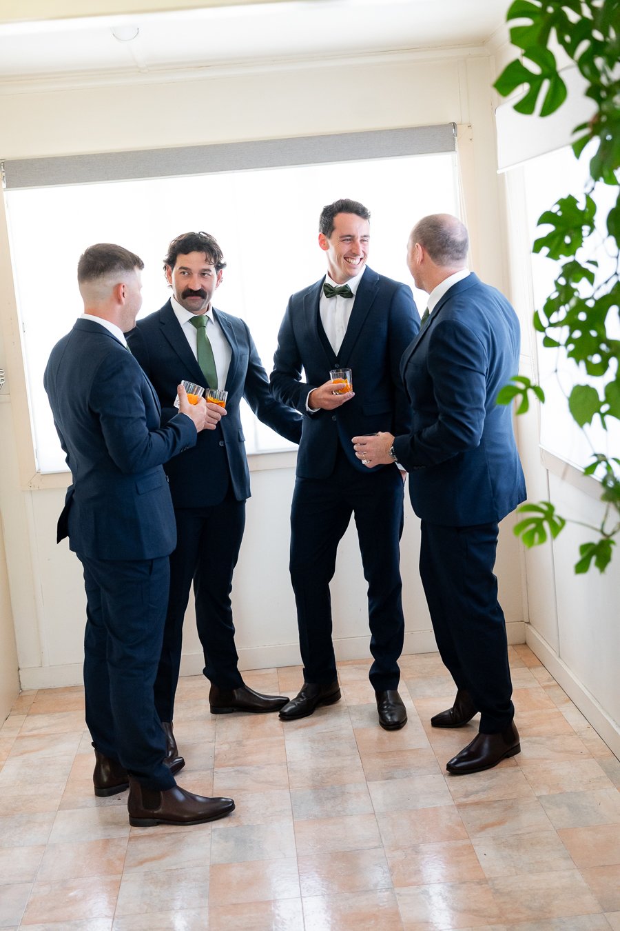 The groomsmen and groom chatted together, each holding a glass