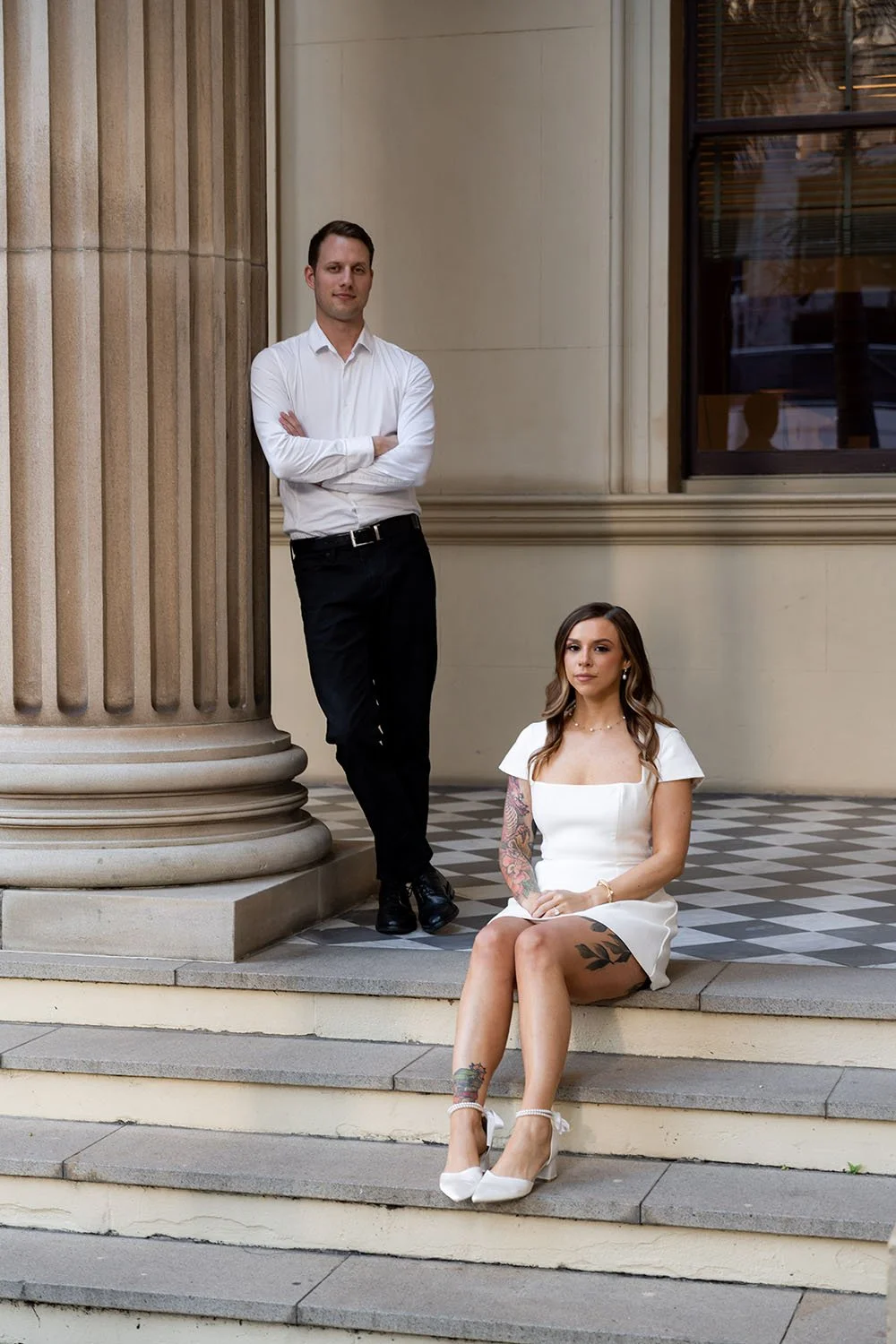 Brenna sitting, Morgan leaning on the pose crossing his arm and look at the camera