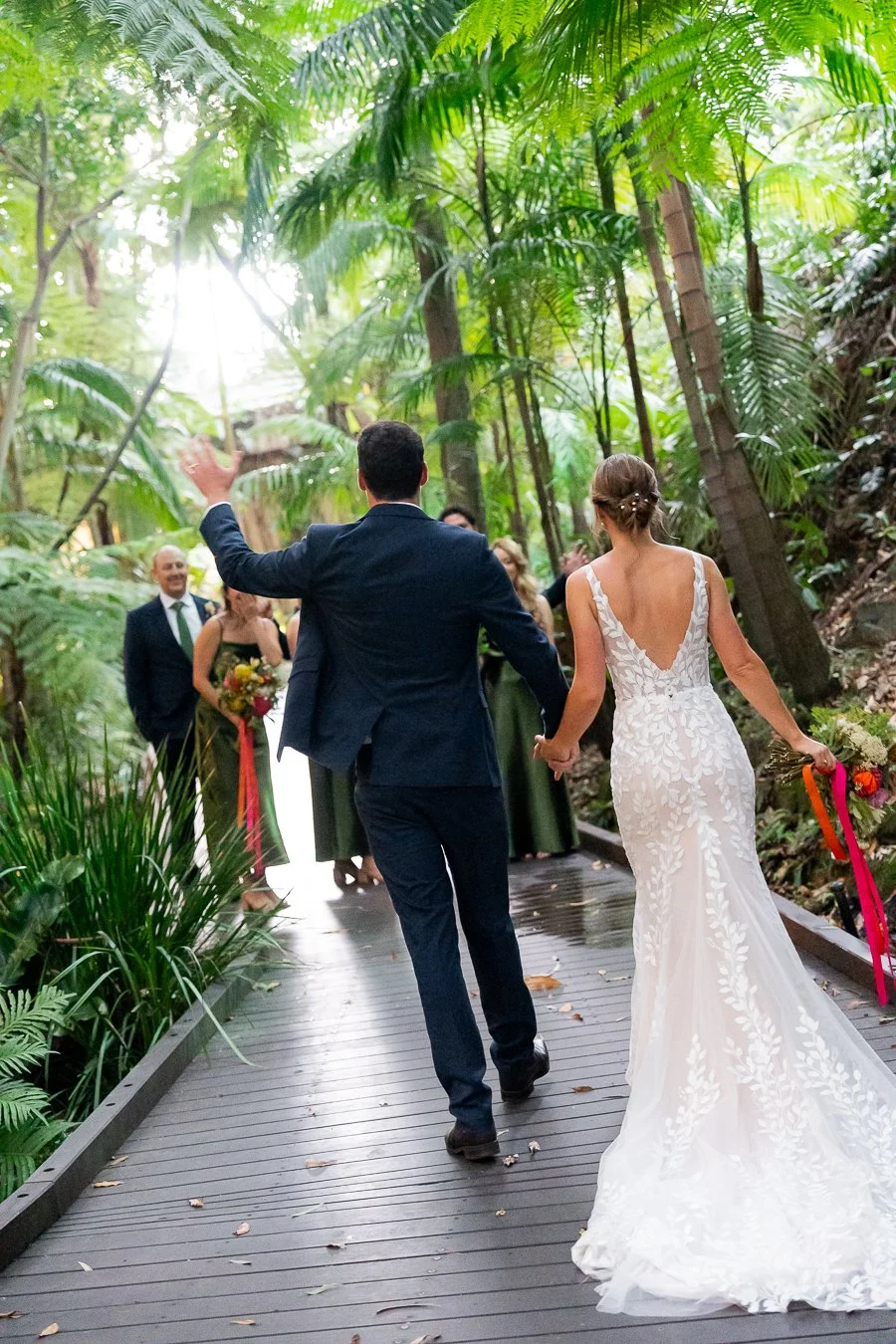 groom Giordan holding bride Sonya's hand wave hands to the bridal party walking towards them