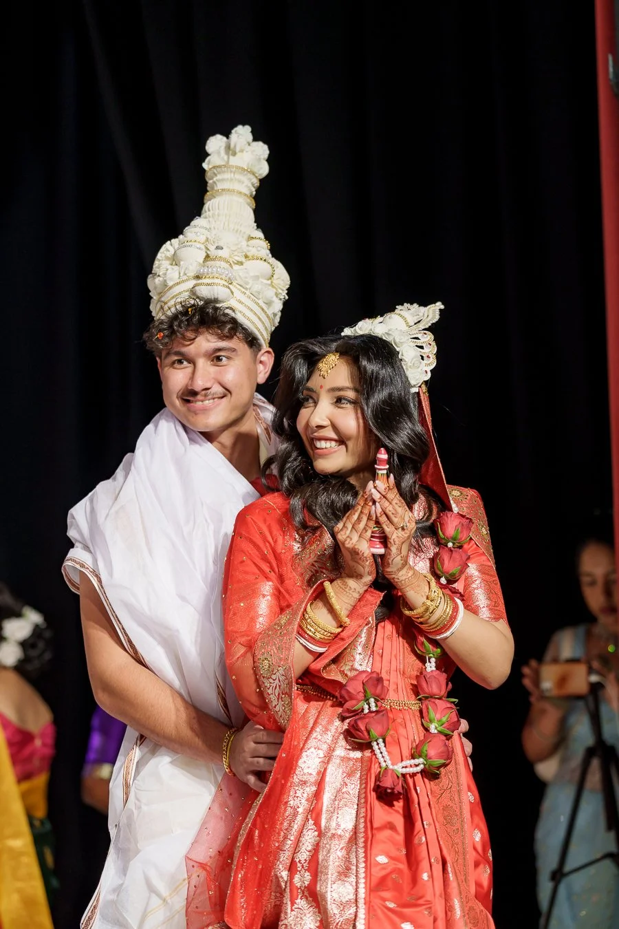 Casey holding Amrita from back when she holding a pray red colourful bottle