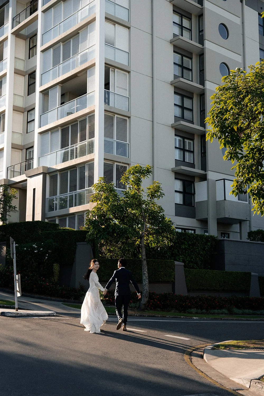 bride look back to the Brisbane wedding photographer when they running on the street under a sunlight