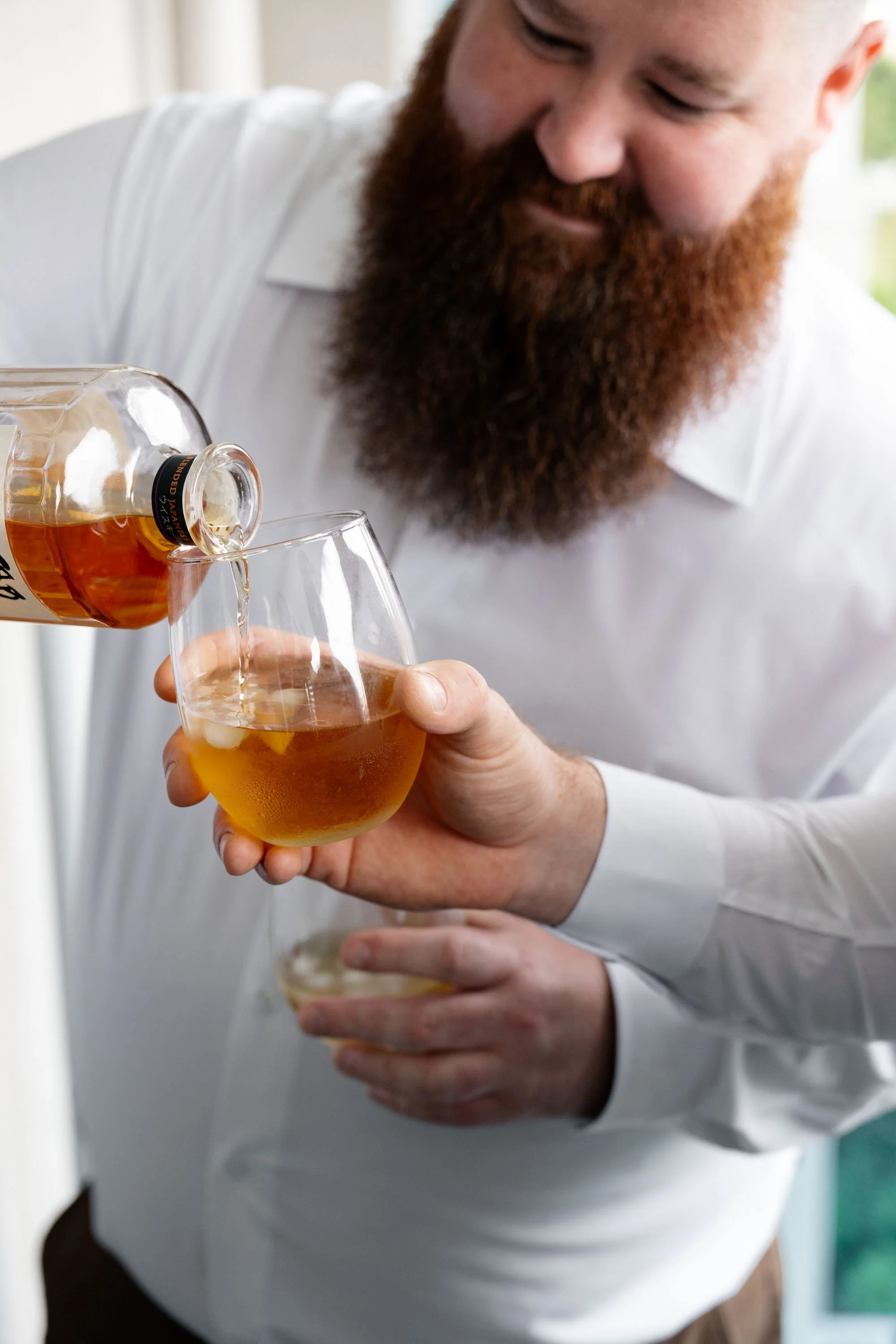 Best man pouring wine into a glass, preparing for a celebratory toast as the wedding festivities begin