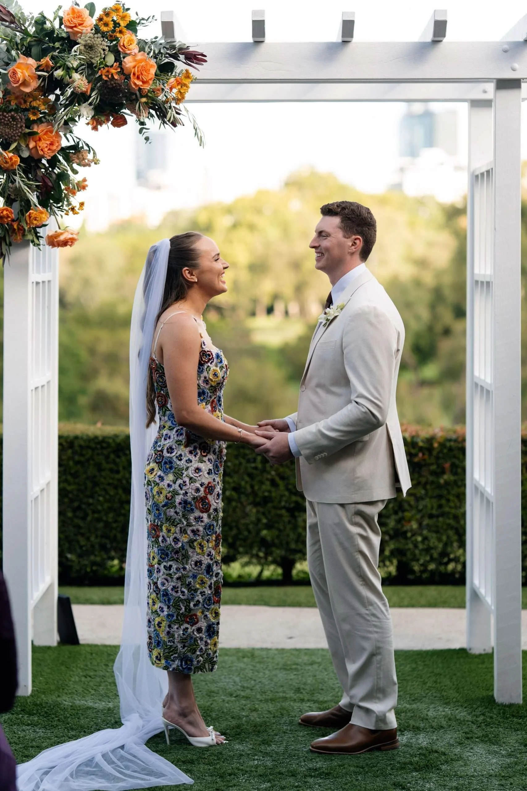 Bride and groom holding hands, laughing at each other with joy
