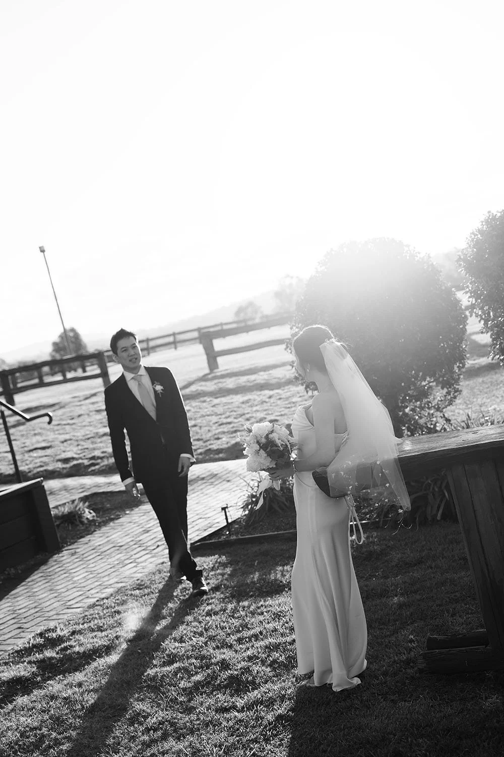 bride Flora leaning on a high table, and groom Eric walking towards to her