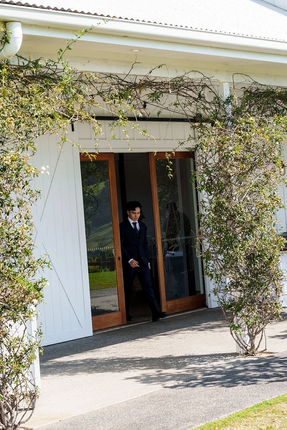 Michael walking out of a glasses door from their reception room in Summergraove estate