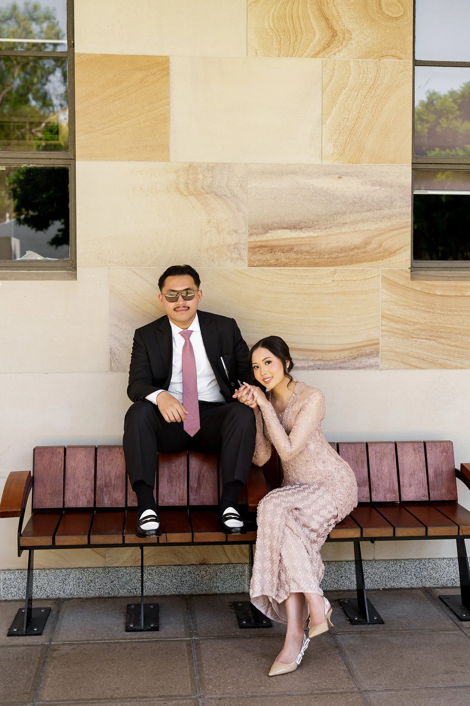 Bella hold Aka look at the Brisbane wedding photographer Whistler Li while Bella sitting on the bench holding his hand