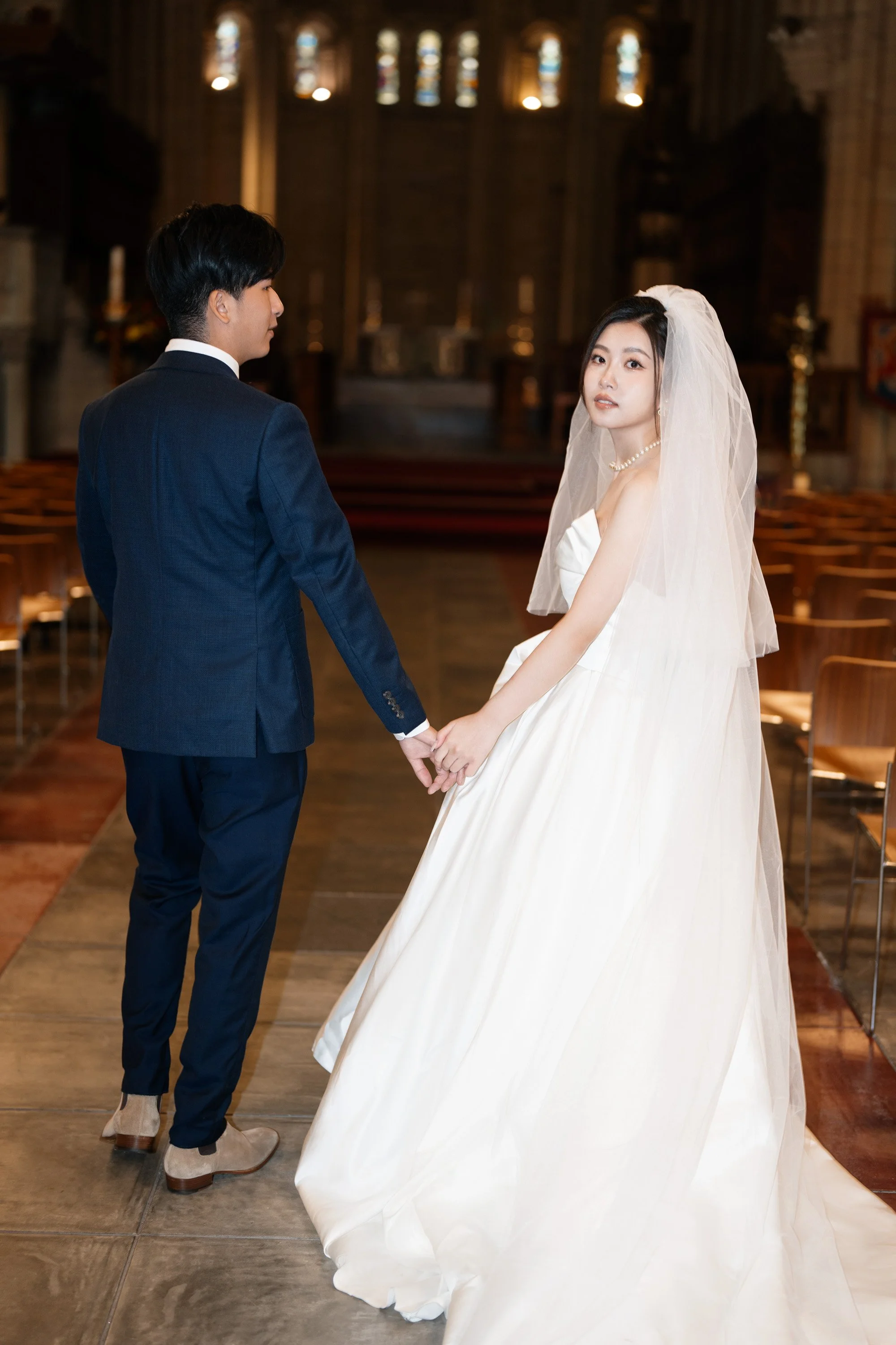bride and groom holding hands and bride look at the camera