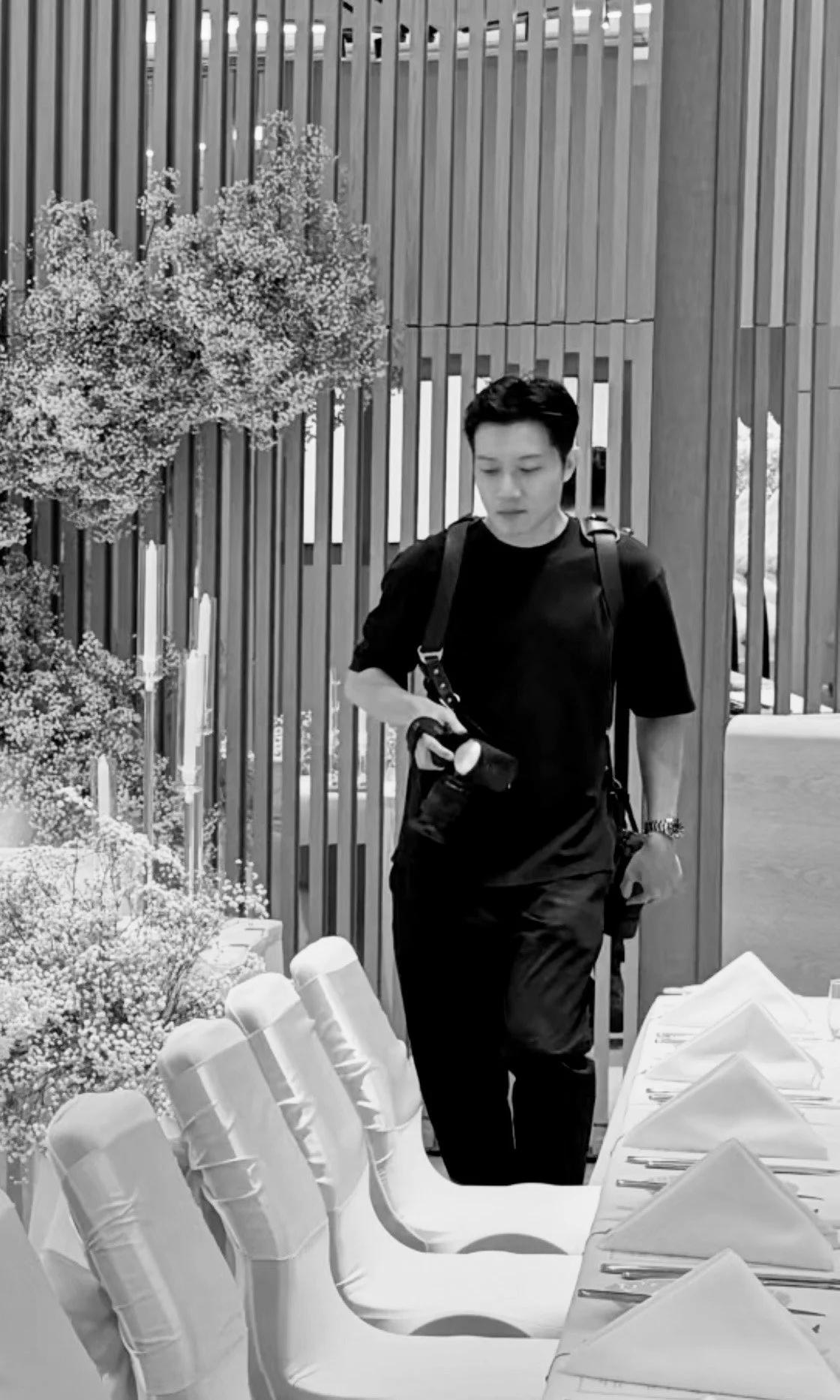 Whistler Li carrying two cameras look down when walking