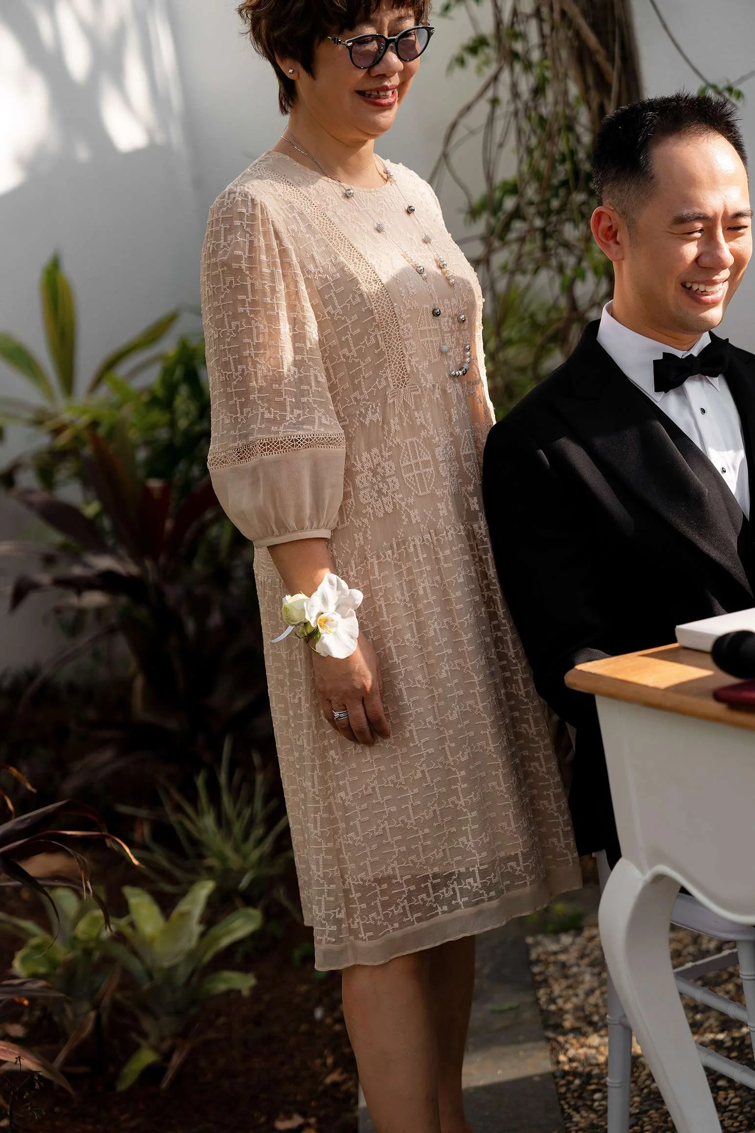 groom mum stand behind him, with a flower on her waist