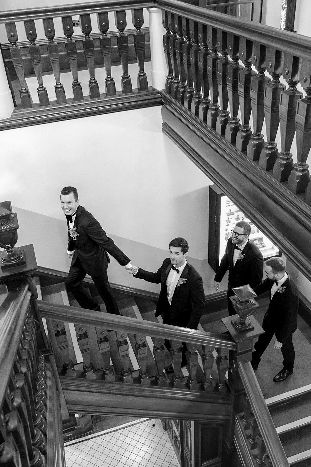 groom Cliffe holding his batsman's hand walking up the stairs and rest of the groomsmen follow