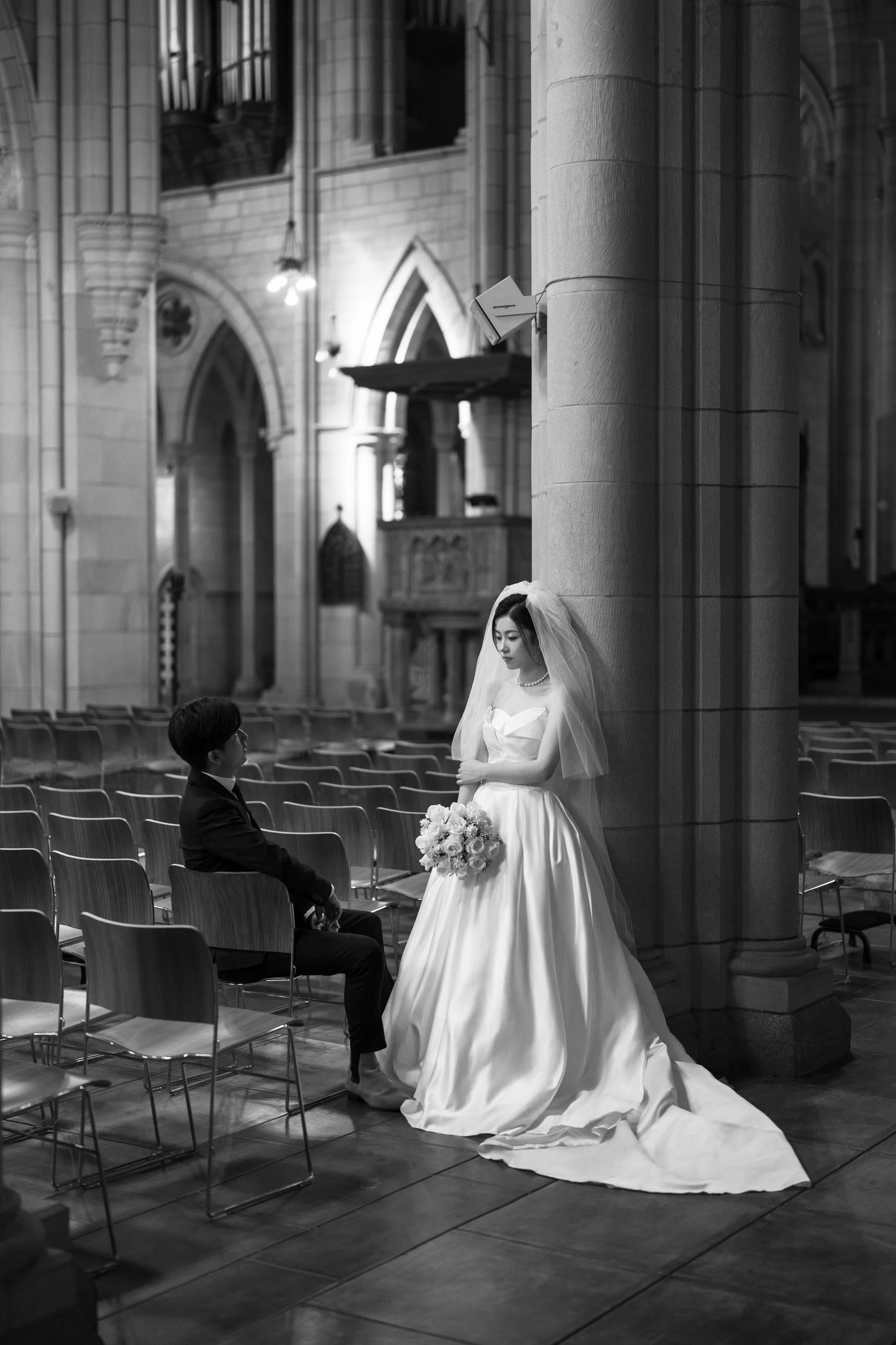 bride Cassie back against the column and groom Leo sitting next to her in St John's Cathedral in Brisbane