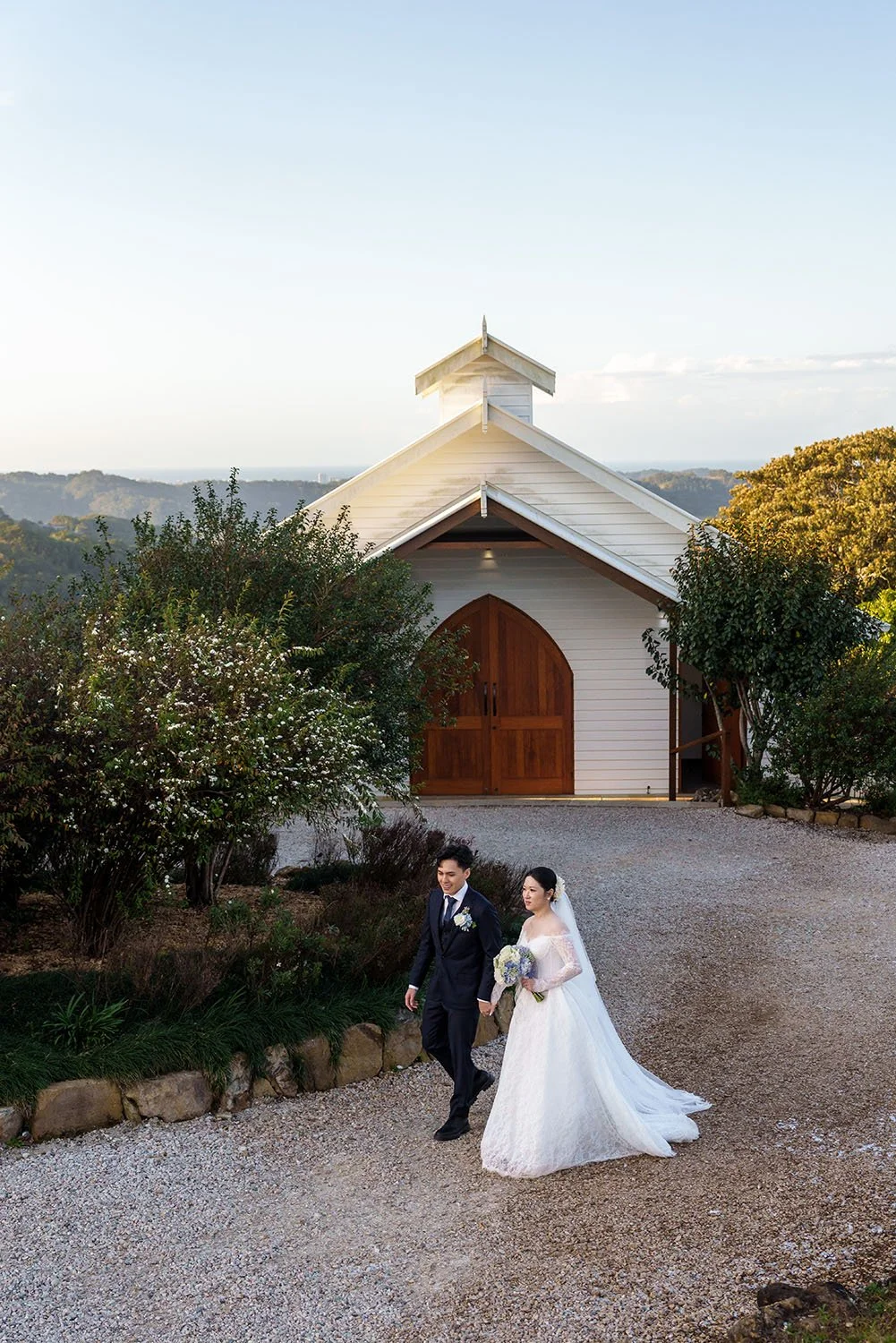 Michael and Lisa holding hands walking in front  of white chapel   