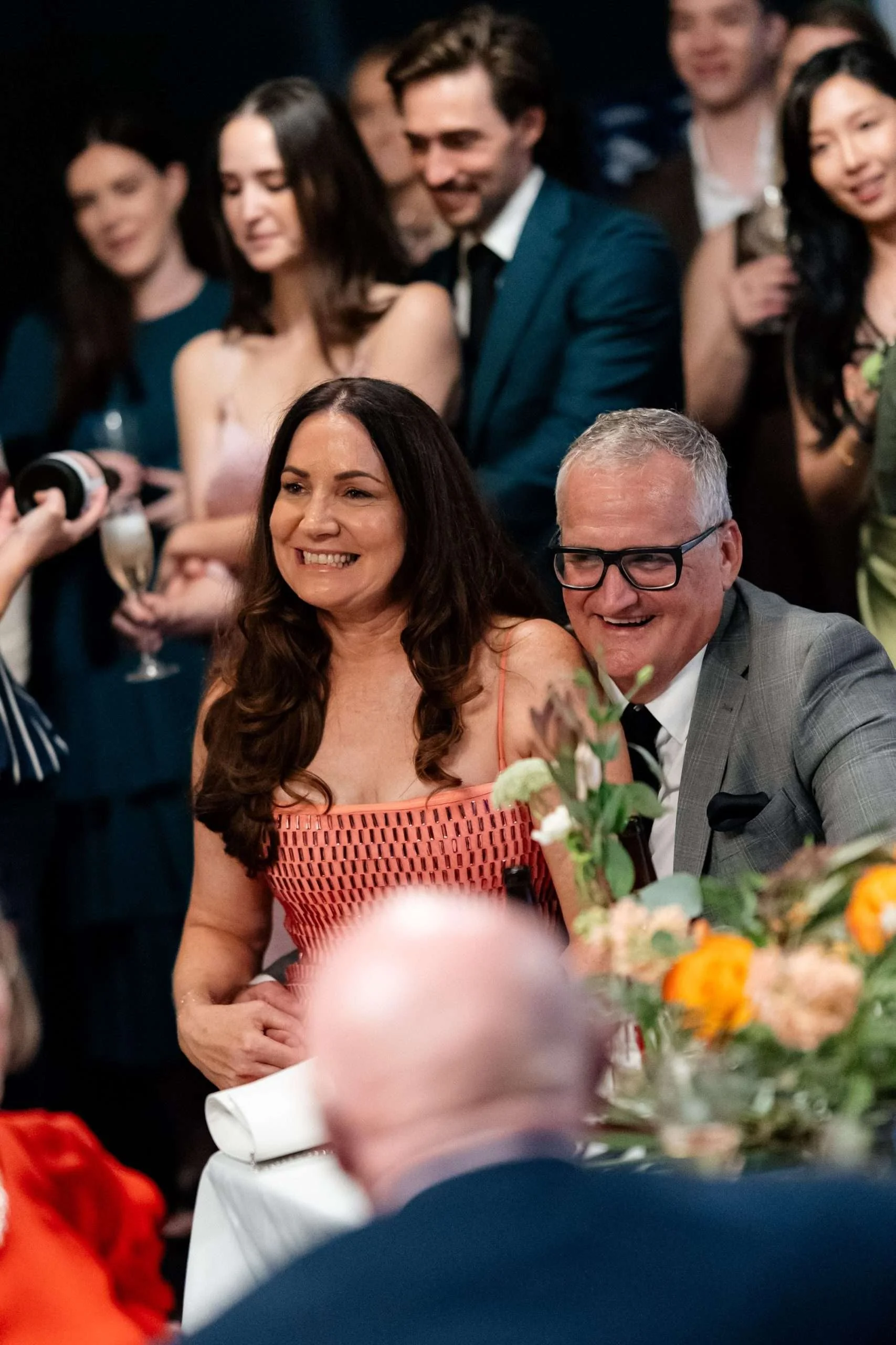 bride's parents sitting together laughing while bride making her speech