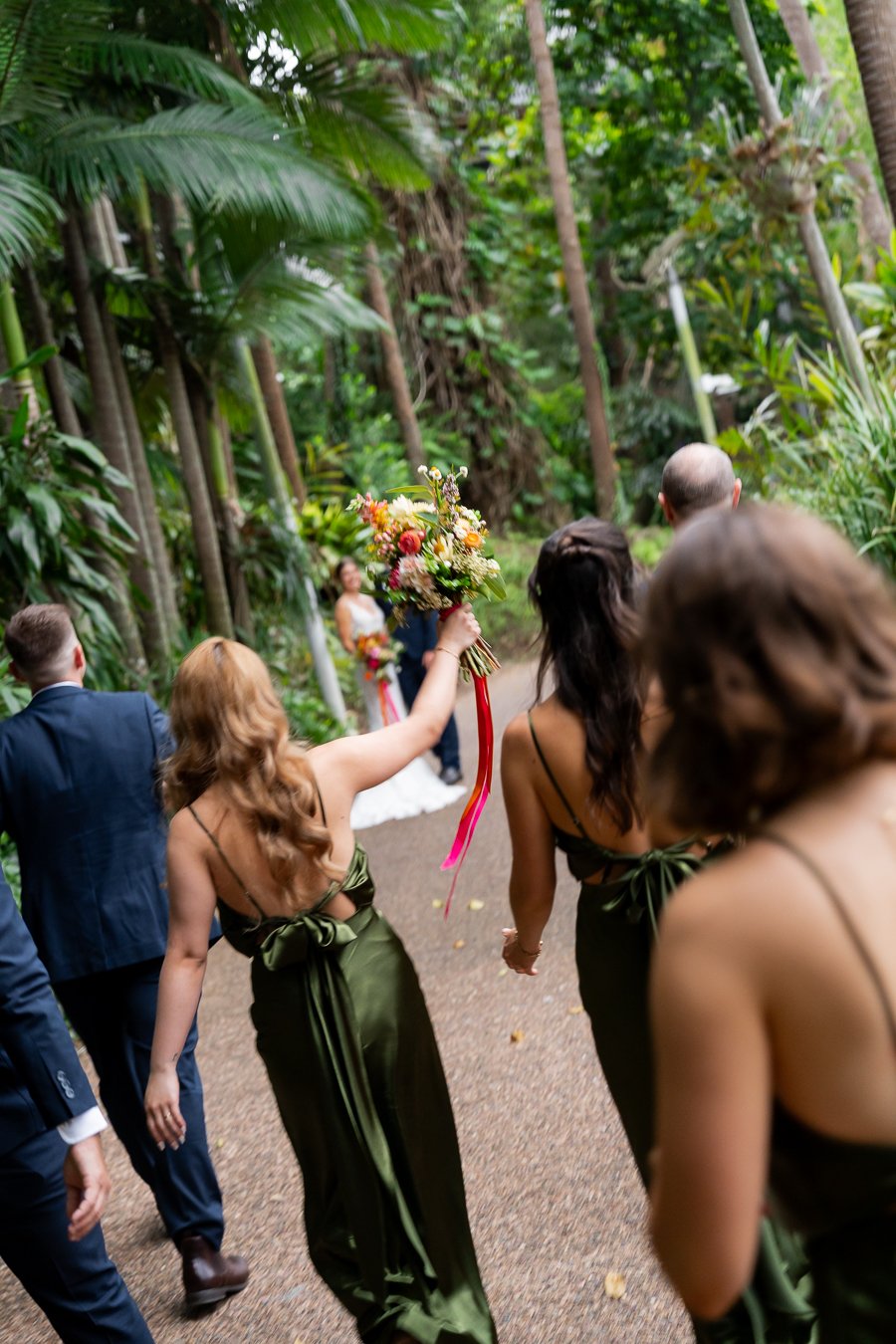 bridal party walking towards to bride and groom with flower up in Roma street parkland