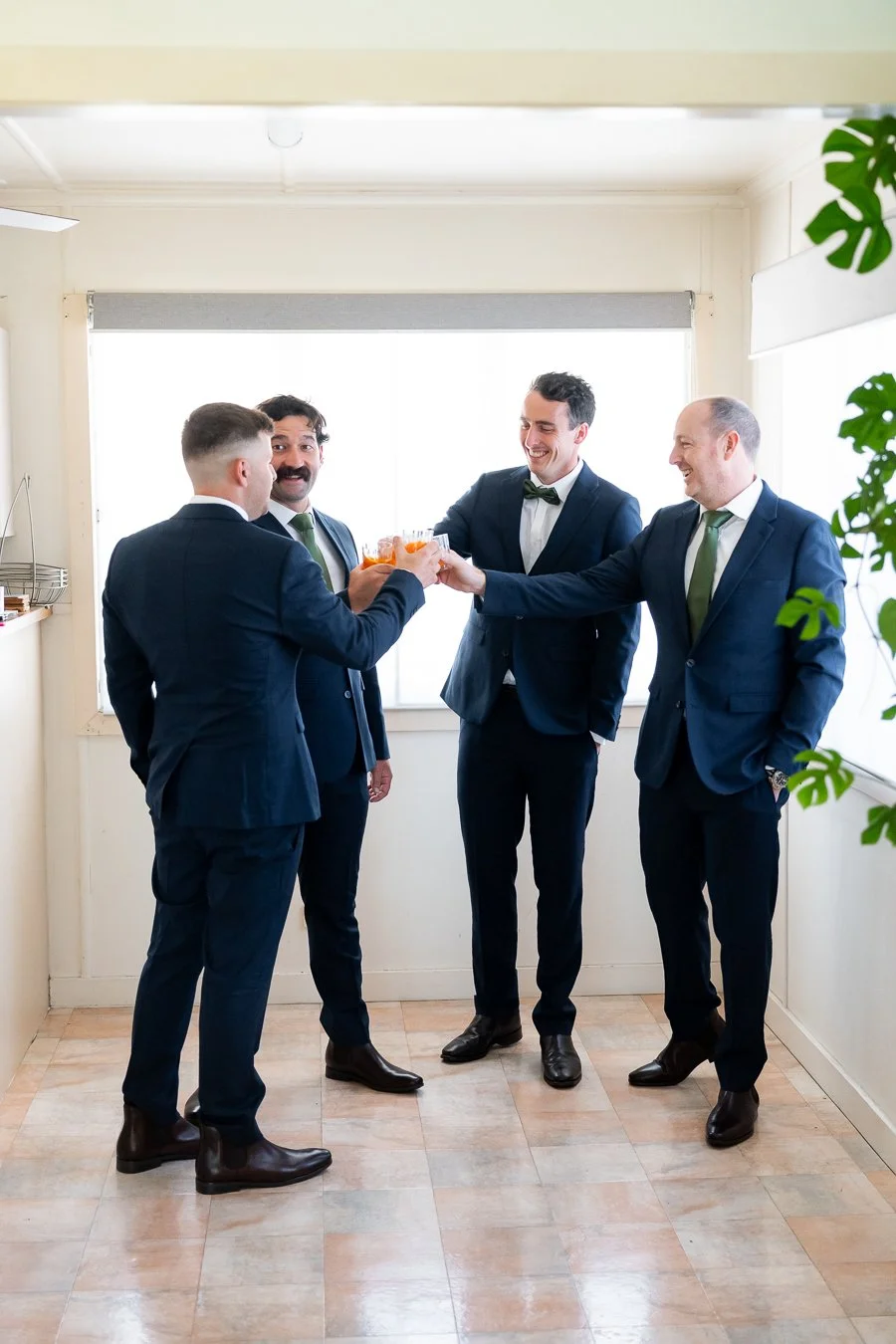 The groom and his groomsmen clinked glasses, all dressed in their suits and ties