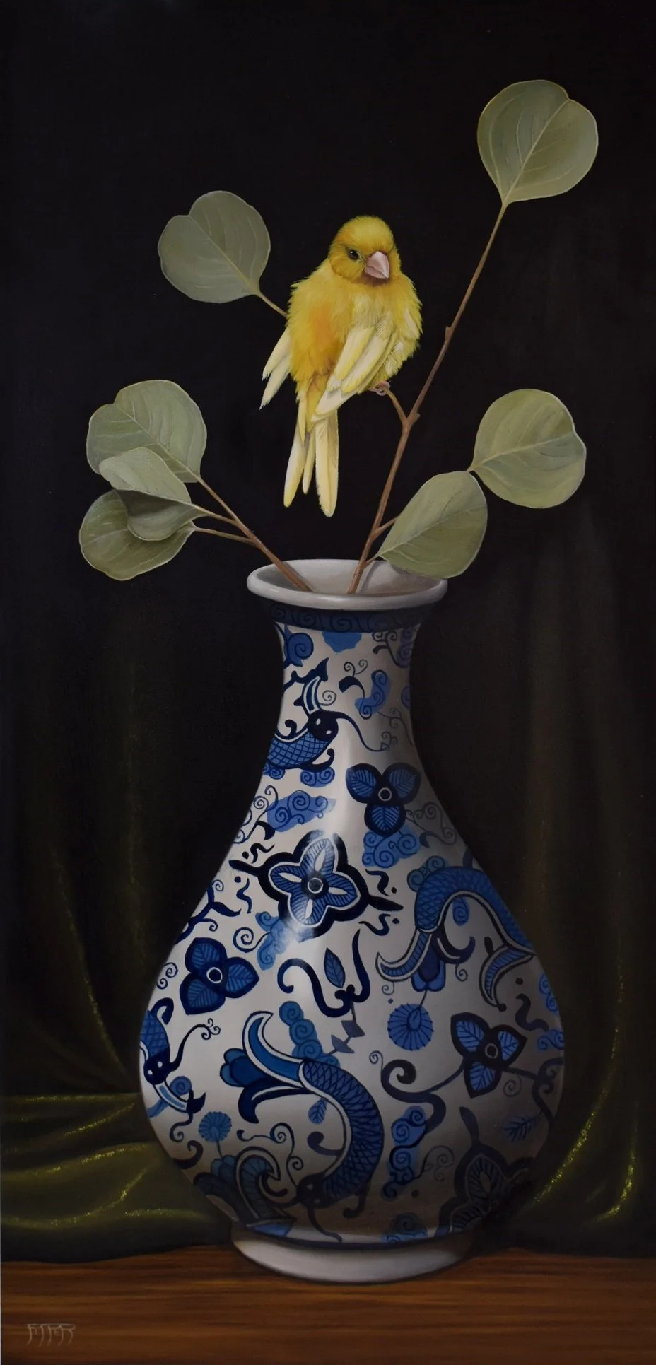 A decorative ceramic vase with blue floral and dragon design, holding a branch with green leaves and a yellow bird perched on it, set against a dark background.