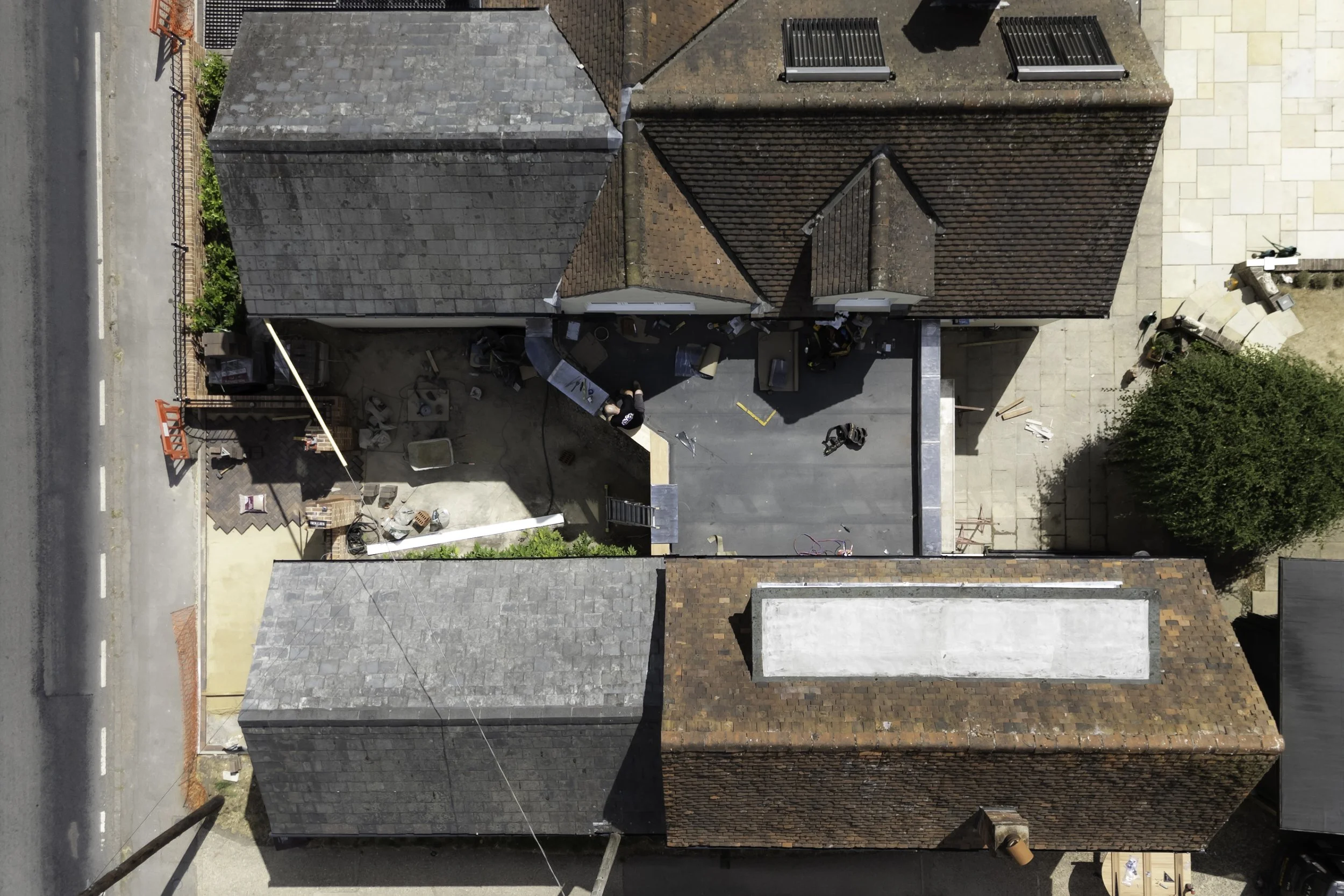 An aerial view of rooftops on a residential street, with construction work visible in a backyard.