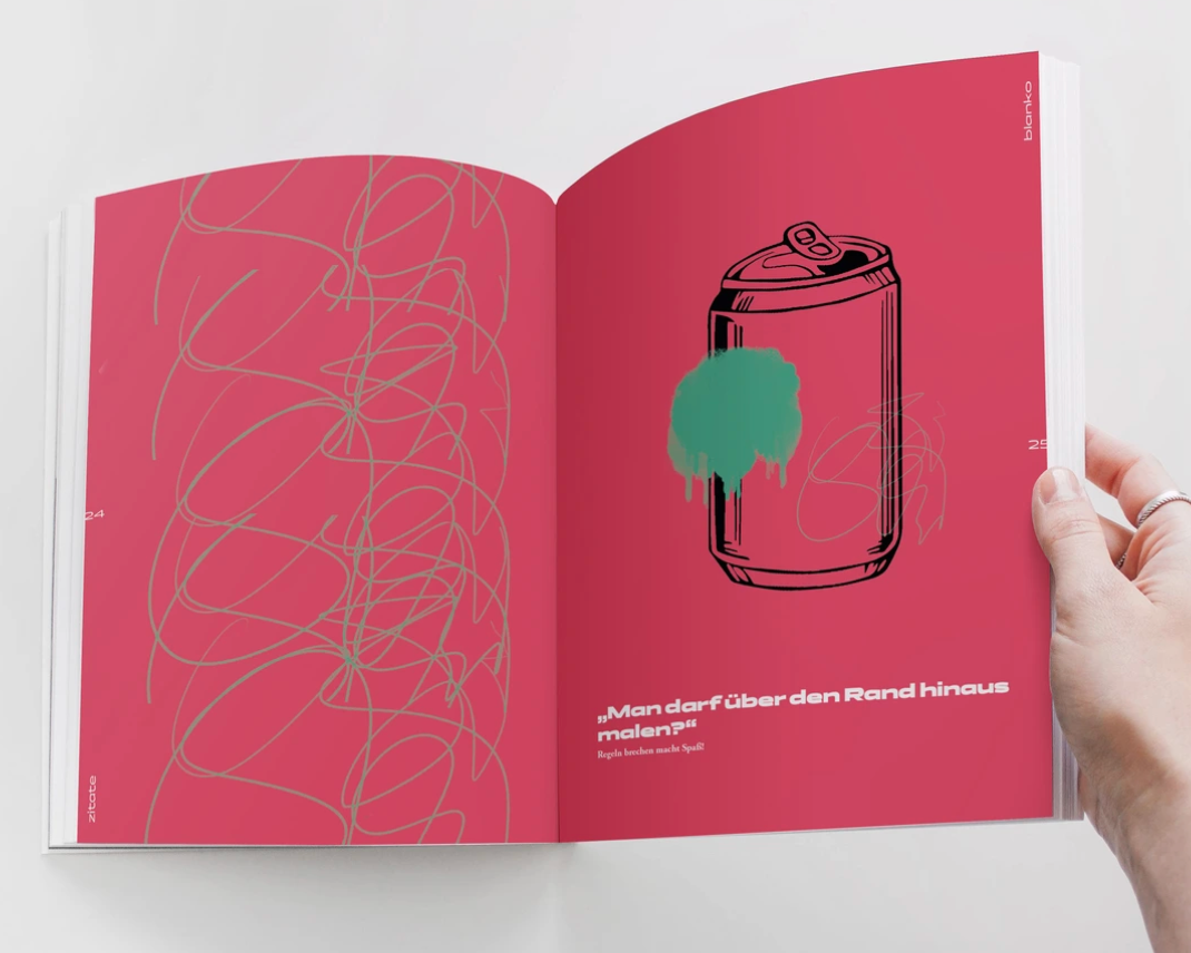 Offenes Buch mit pinken Seiten. Die rechte Seite zeigt eine schwarze Skizze einer Dose mit grüner Sprühfarbe. Darunter steht ein Zitat auf Deutsch.