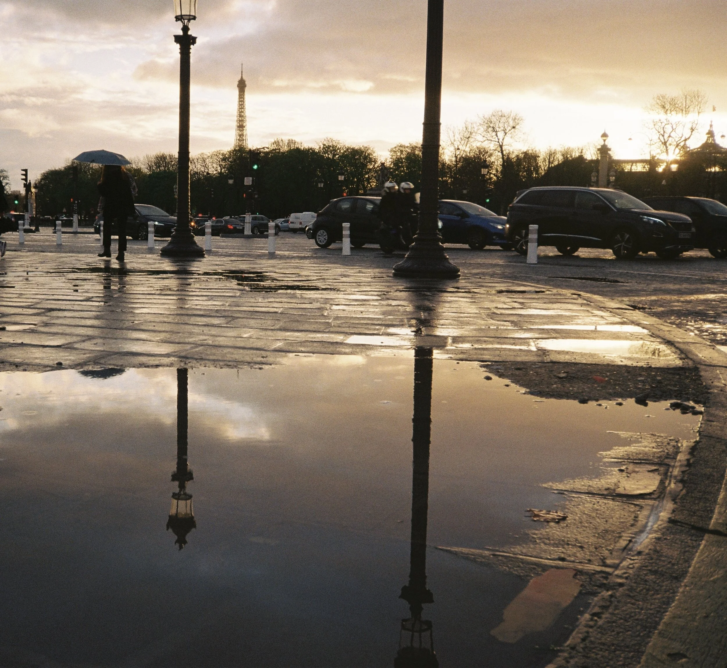Straßenlaternen, और लोग mit Regenschirm, Autos, Bäume und die Eiffelturm im Hintergrund bei Sonnenuntergang oder Sonnenaufgang in Paris, Frankreich.