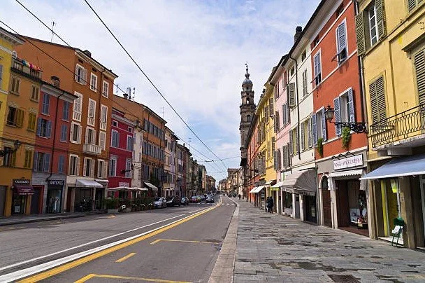 Strada con edifici colorati e negozi, con una torre alta sullo sfondo.