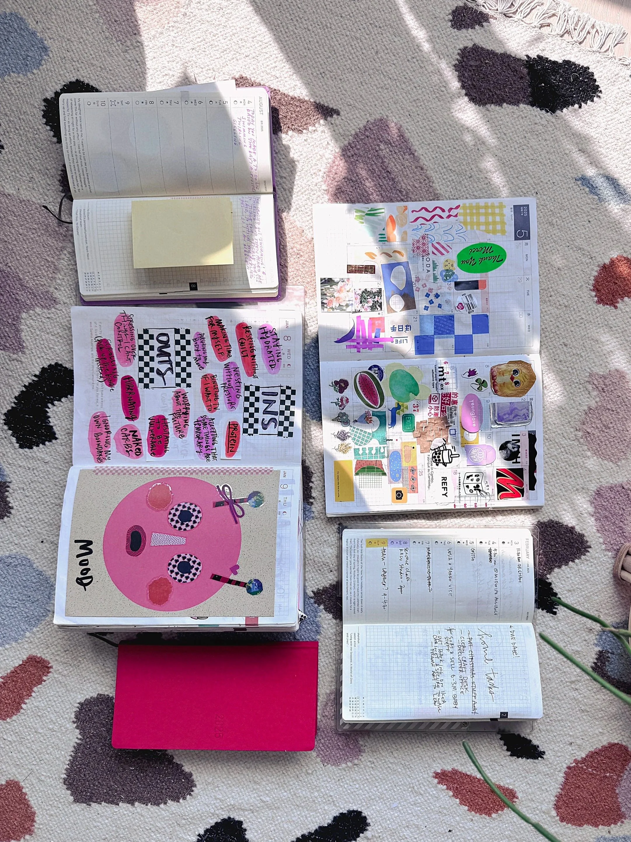 A collection of creative journals lay open on a colourful rug