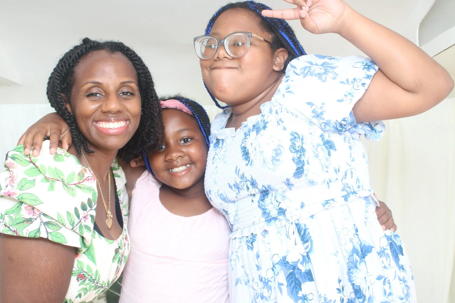 Three women and a young girl smiling and taking a group selfie indoors.