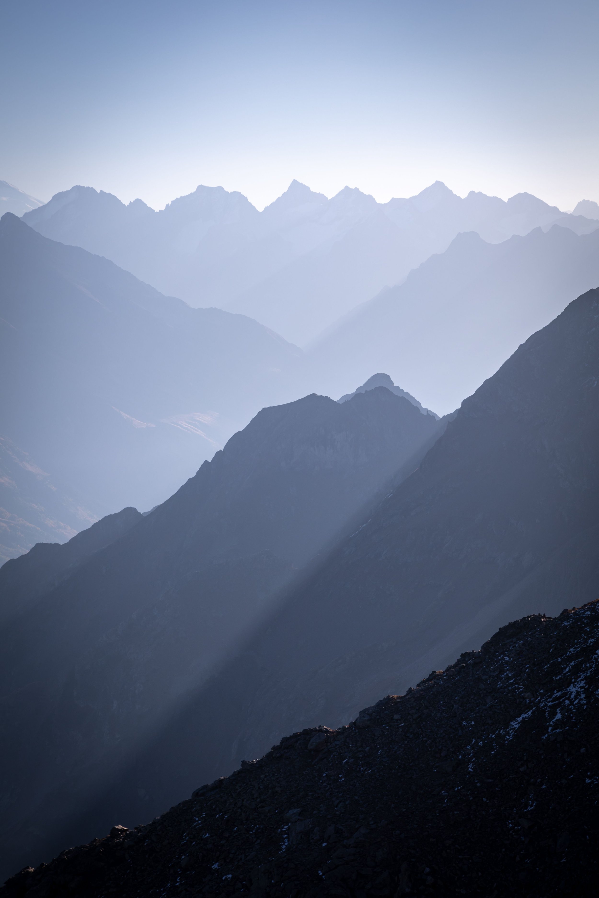 Majestic mountain range with layers of peaks fading into the distance, under a clear sky.