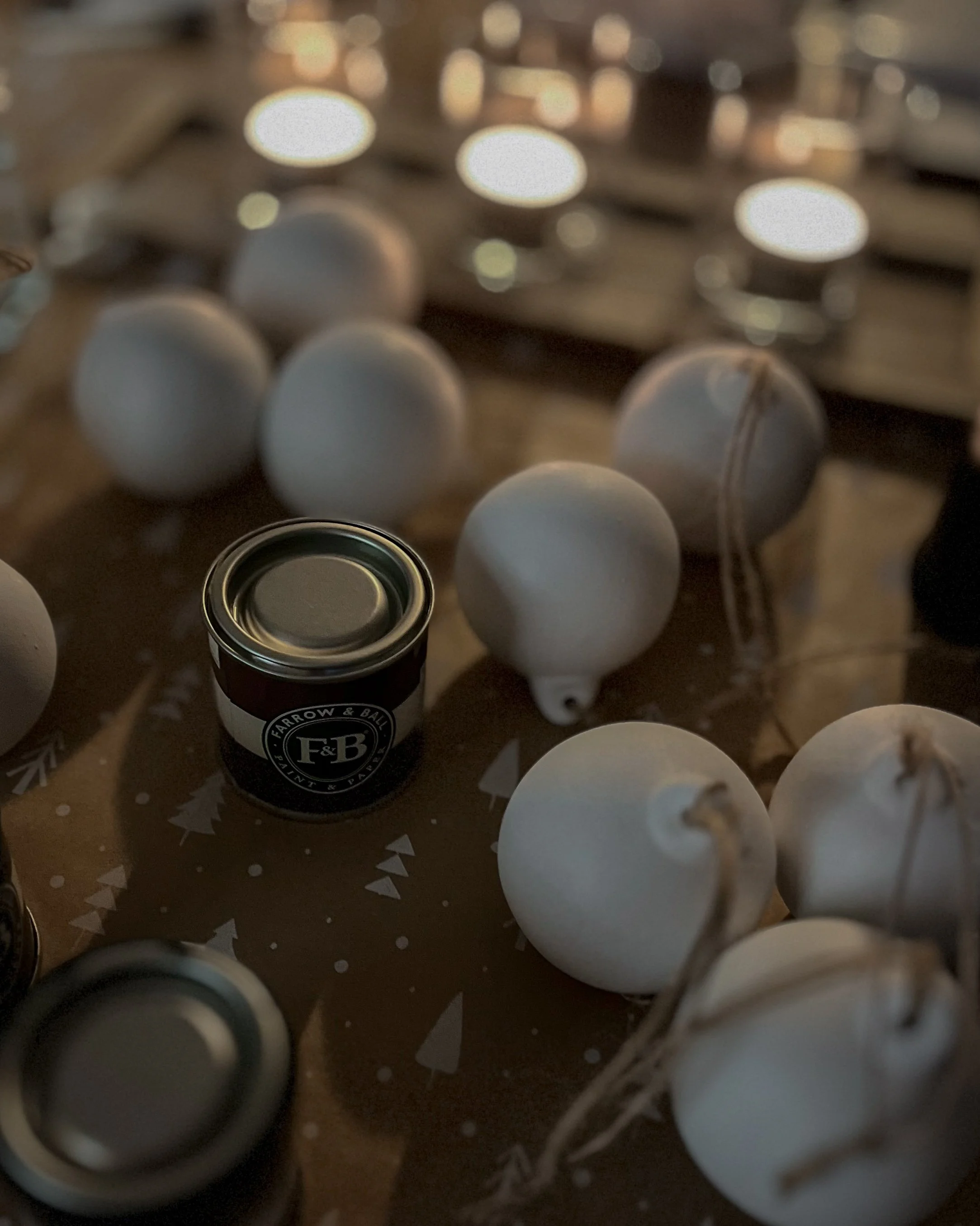 Behind the scenes of creating bespoke ceramic Christmas baubles, with paints and undecorated baubles arranged in the artist's studio.