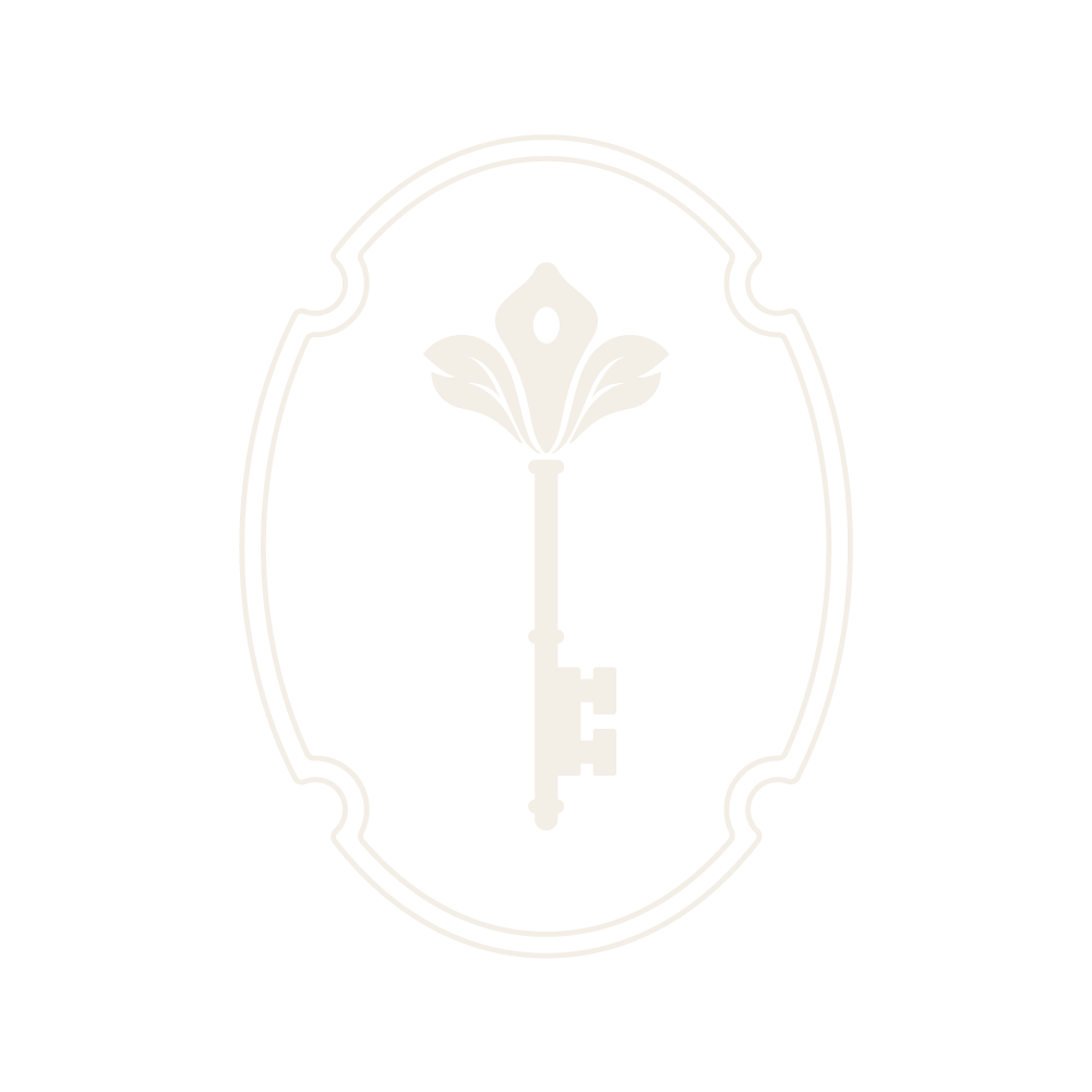 A white vintage-style key with a floral design on top, centered within an ornate oval border on a black background.