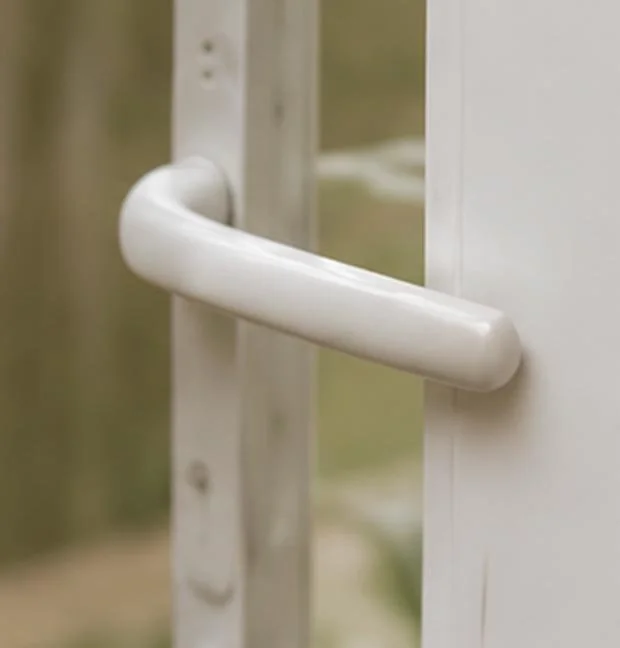 Close-up of white door handle on glass door in a building.