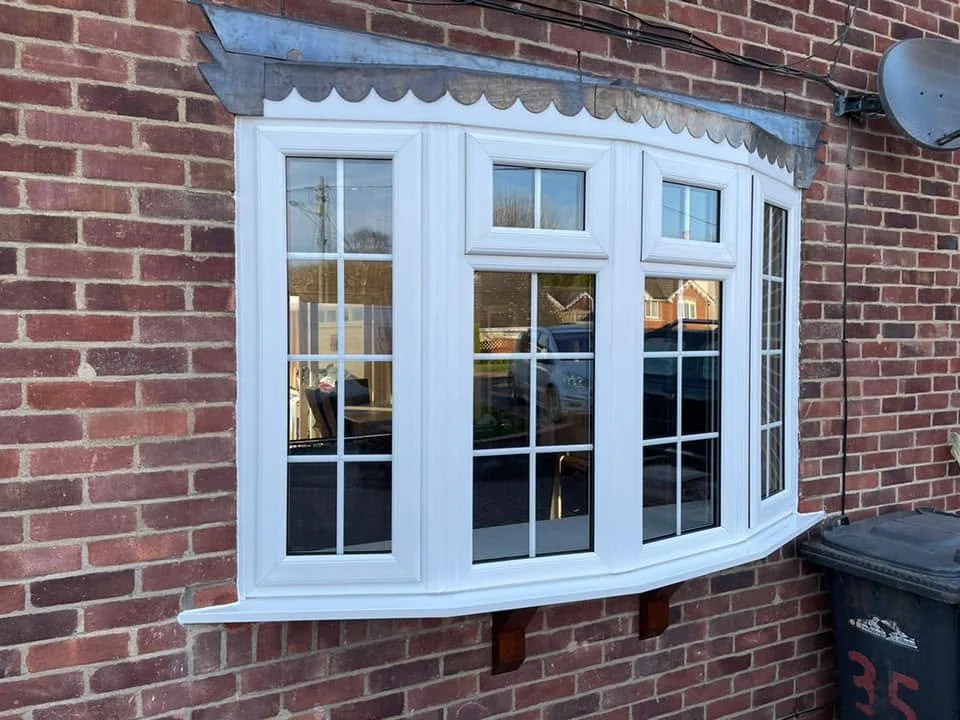 White bay window with multiple panes mounted on a brick exterior wall.