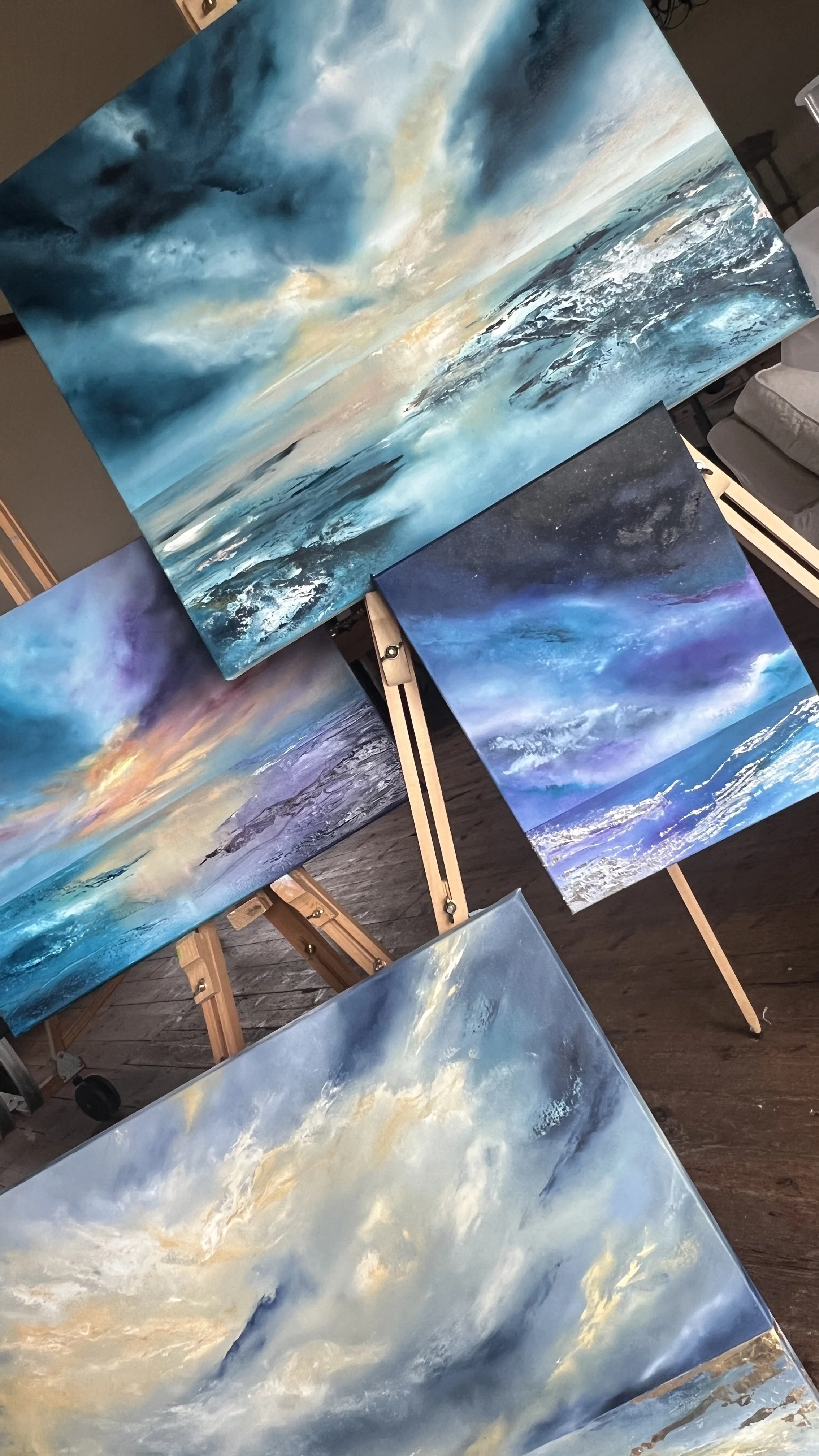 Collection of oil paintings depicting ocean waves and sky scenes, with vibrant blues, whites, and hints of warm colors.