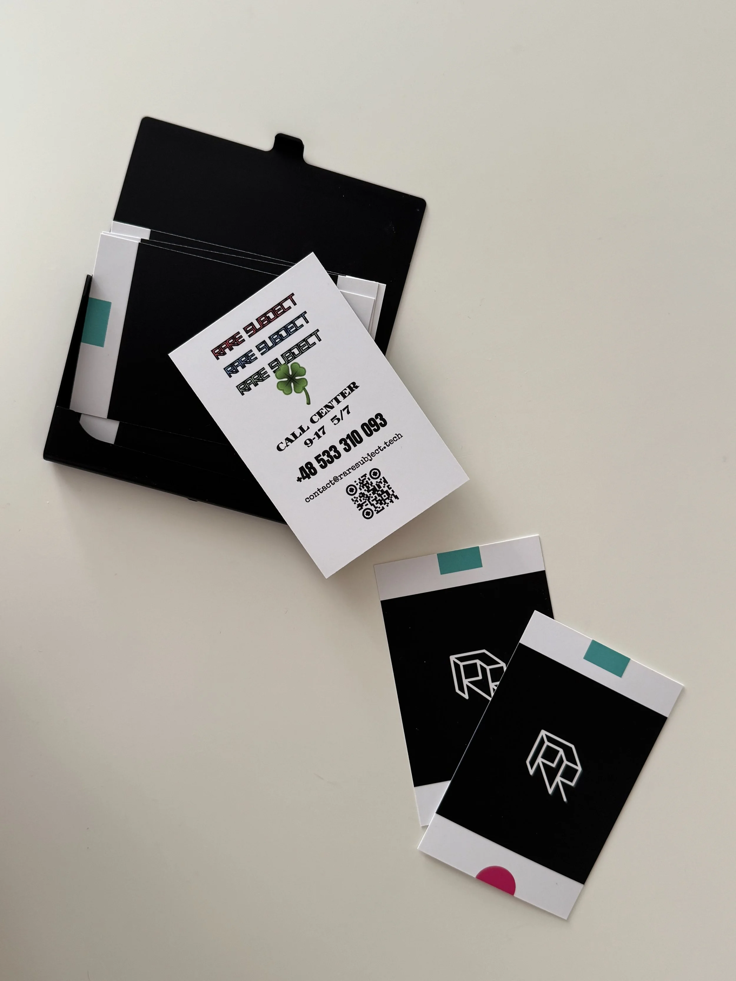 Business cards with black and white backgrounds, some feature geometric logos and colorful accents, spread out on a white surface.