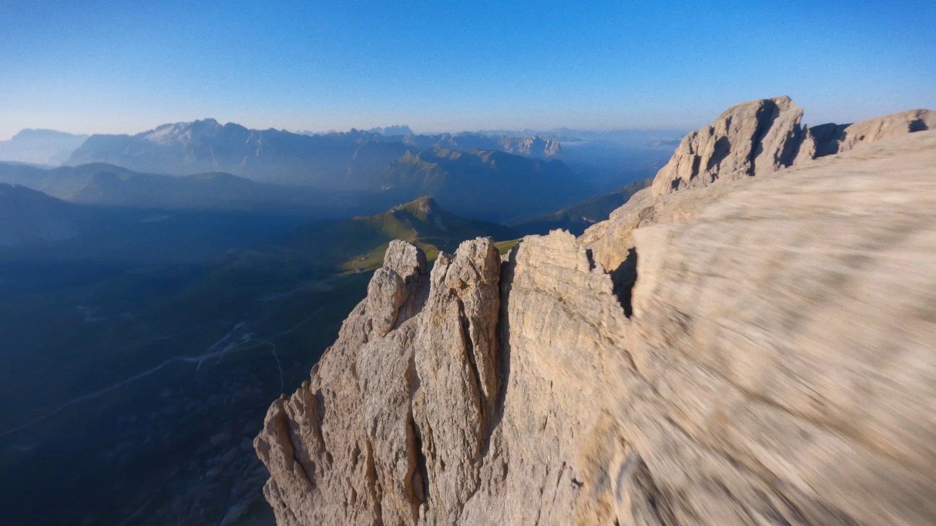 A mountain range with rocky peaks and green valleys under a clear blue sky.