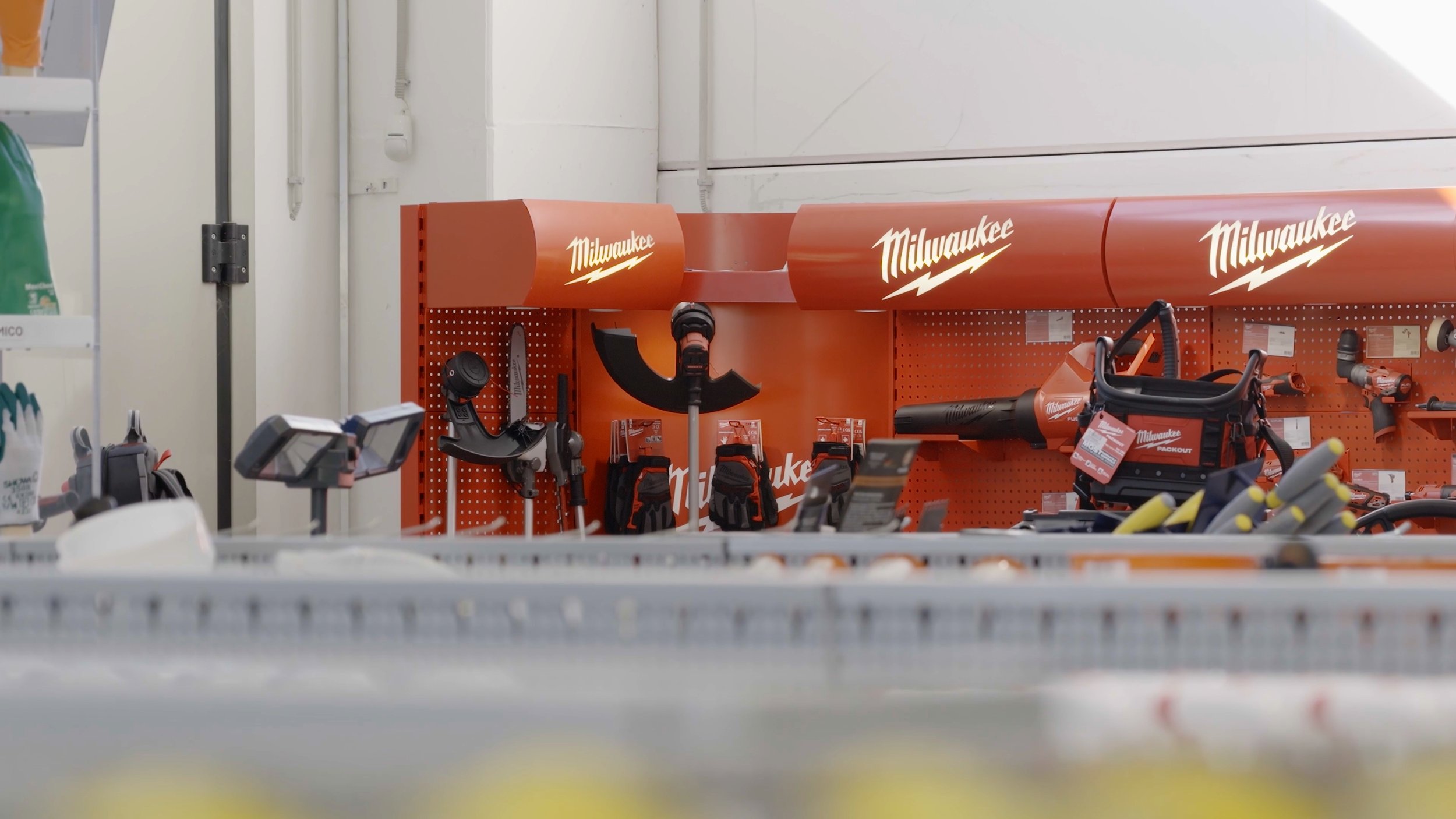 Store aisle display of Milwaukee tools and equipment, including power tools, on orange shelves with Milwaukee logo.