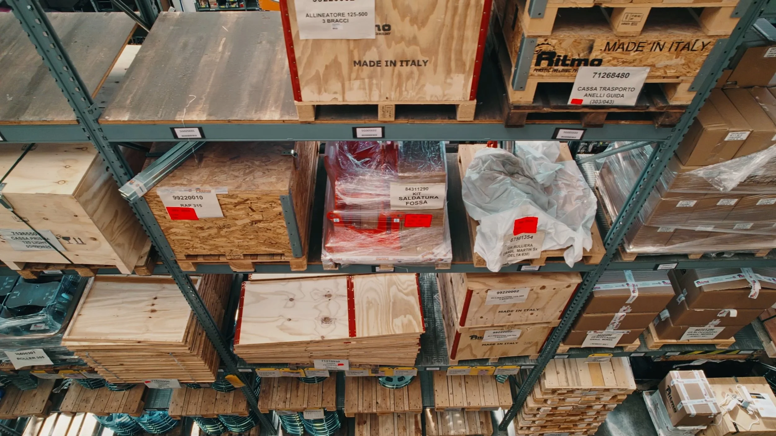 Warehouse shelves stocked with wooden boxes labeled 'Made in Italy' and other packaging materials.