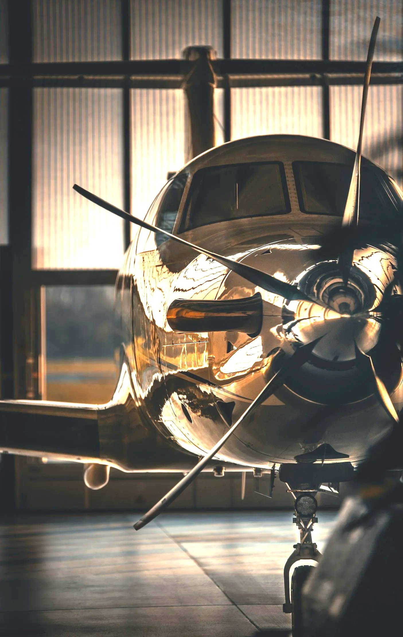 An airplane inside a hangar with sunlight shining through the windows, reflecting off its shiny surface.