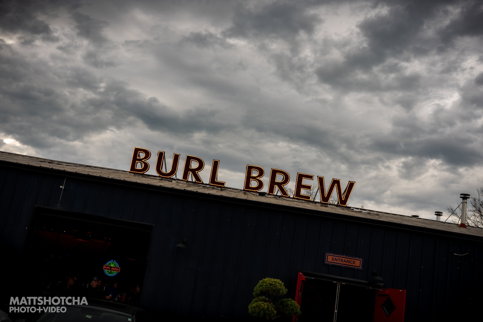 Sign for Burl Brew at The Burl in Lexington, Kentucky with cloudy sky in background.