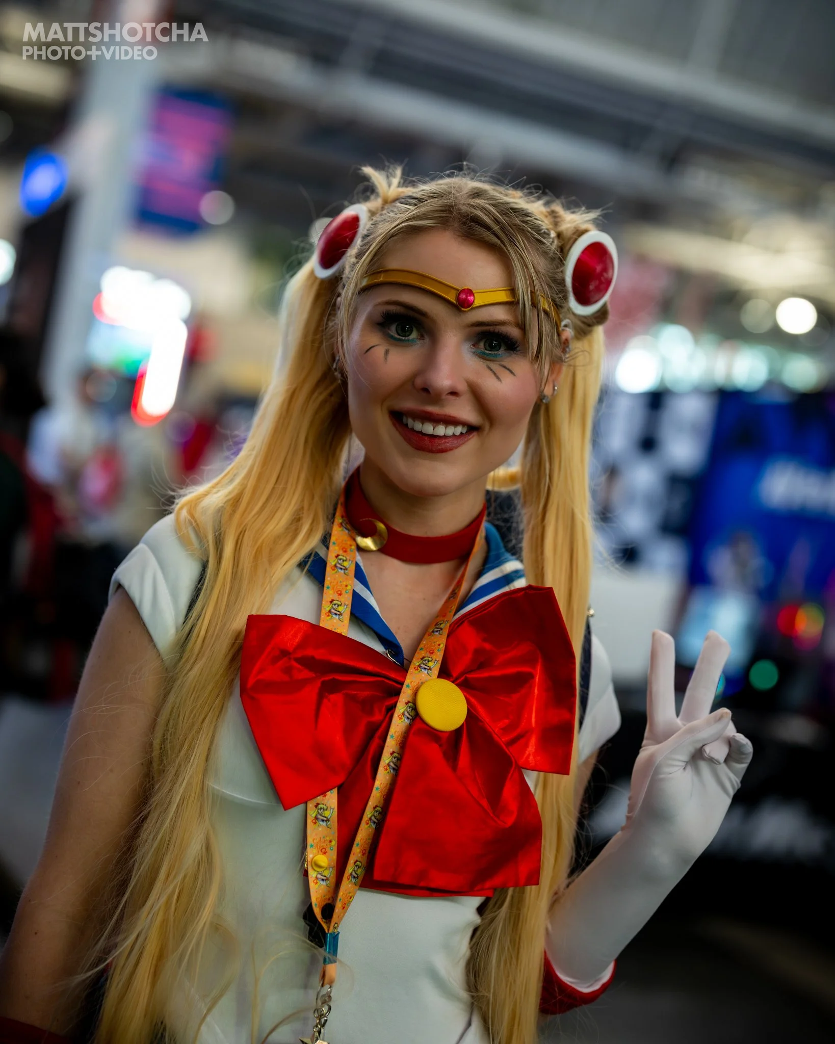 A woman dressed as Sailor Moon smiling and making a peace sign with her gloved hand at PAX East 2026.