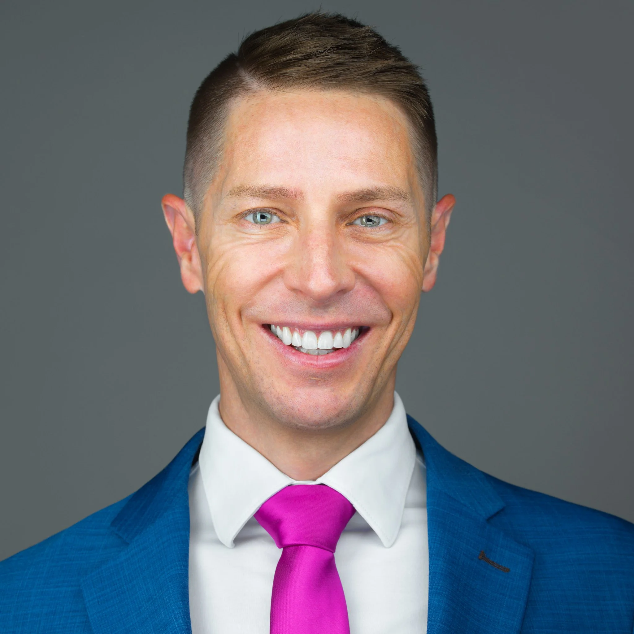 Steven Taylor Headshot Blue Jacket Pink Tie Gray Background