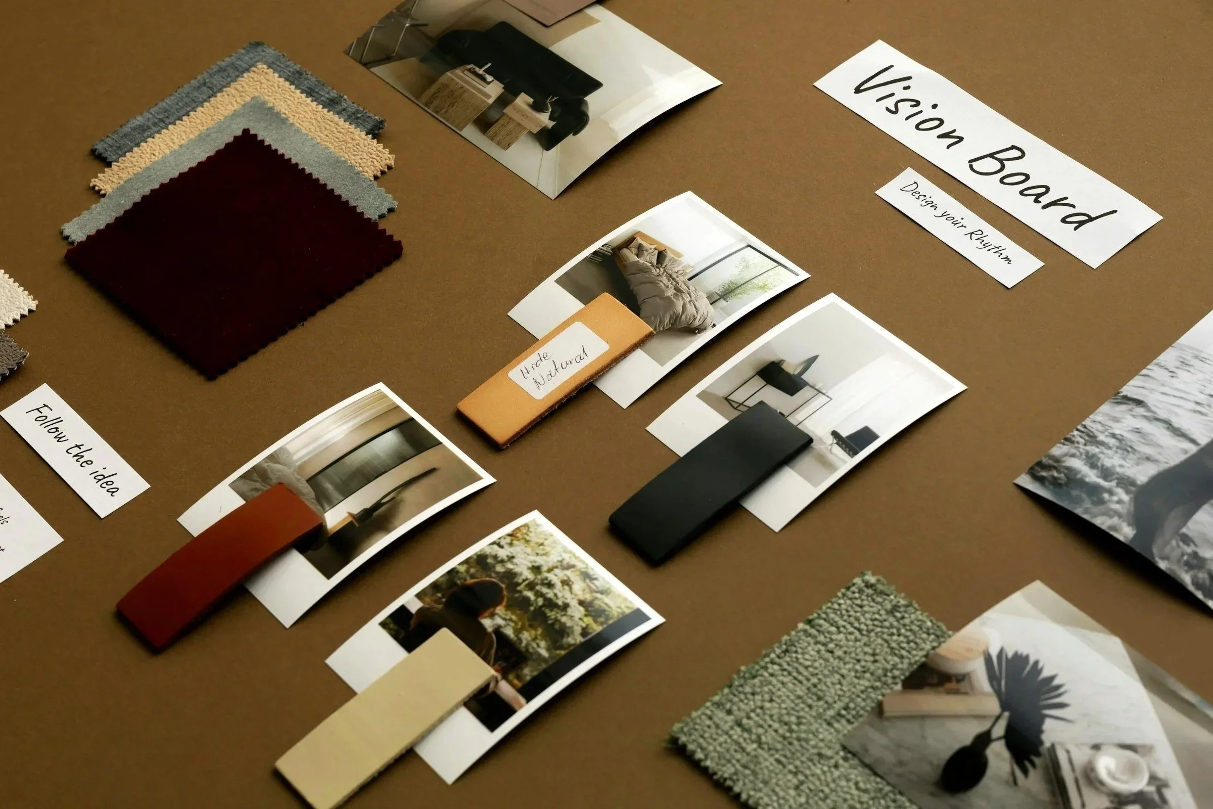 Mostra amostras de tecidos, paletas de cores, fotografias de ambientes decorados, uma régua de cor com o rótulo 'Ideia Natural', e uma faixa com o texto 'Design Your Rhythm' em uma mesa de design de interiores.