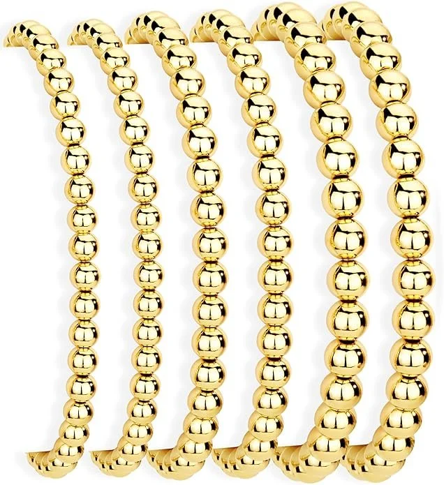 Multiple gold beaded necklaces hanging against a white background.