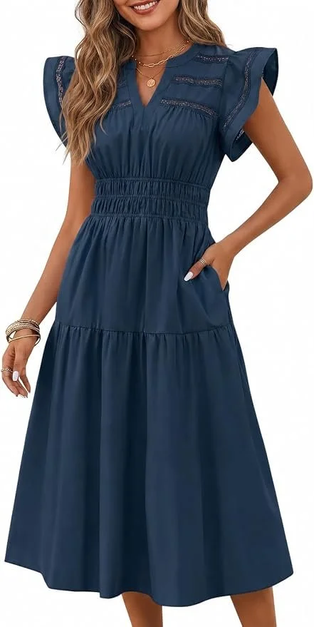 Woman wearing a blue, short-sleeved, maxi dress with lace details and gathered waist, posing with her right hand in her pocket.