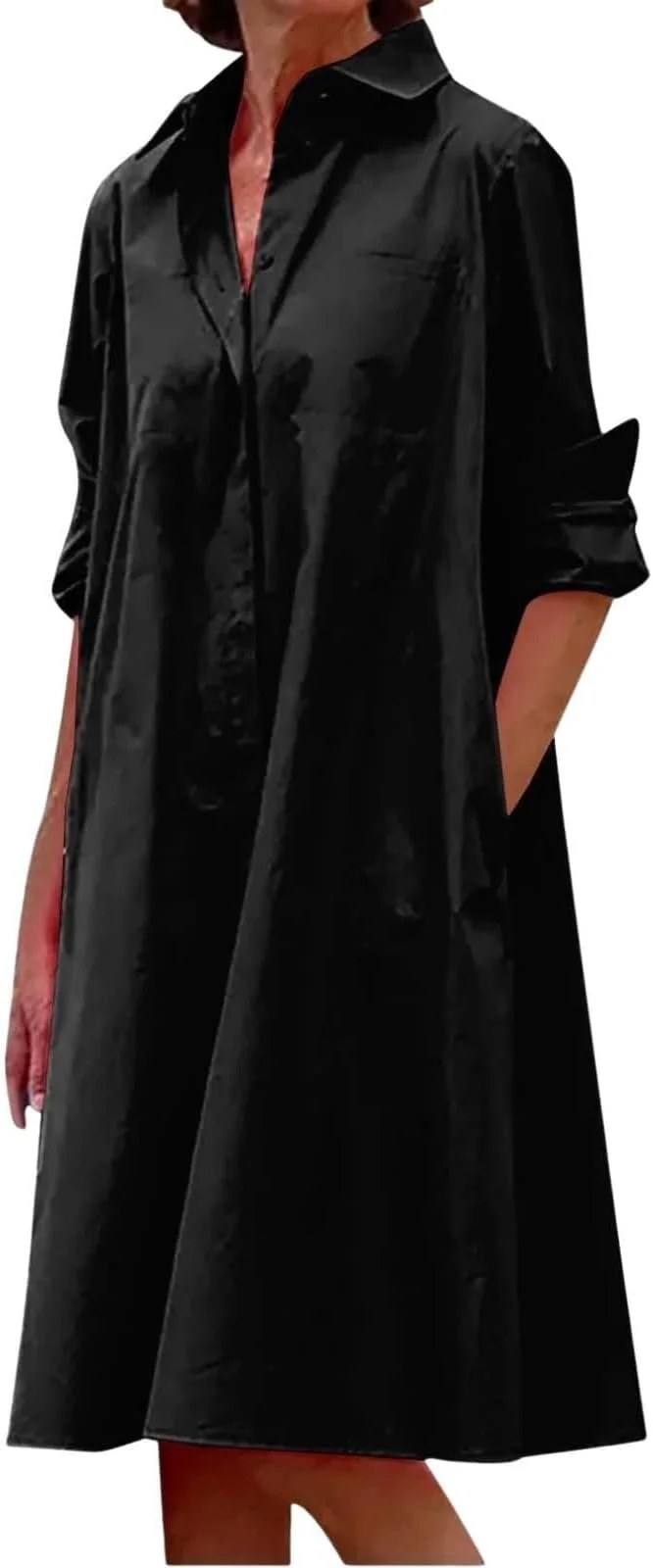 A woman wearing a black shiny long coat with her hands in the pockets.