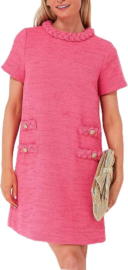 A woman wearing a pink textured short-sleeve dress with decorative buttons and a ruffled neckline, holding a beige clutch purse.