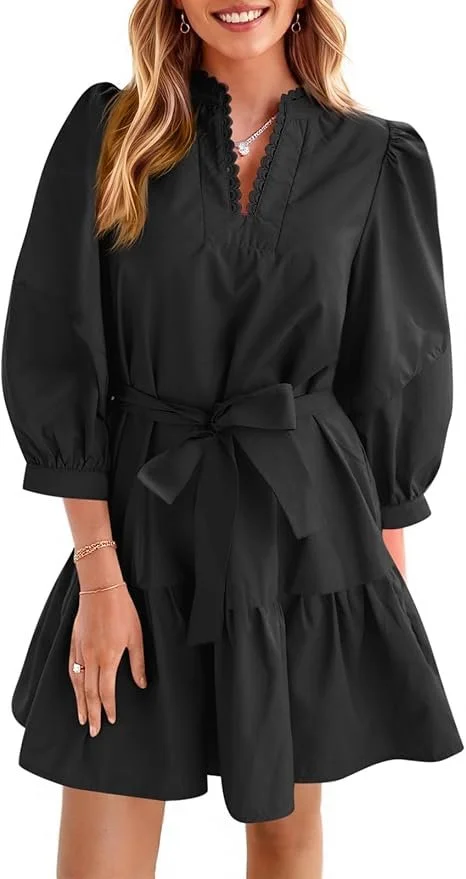Woman in a black dress with puff sleeves and a tied waist, smiling and wearing jewelry.
